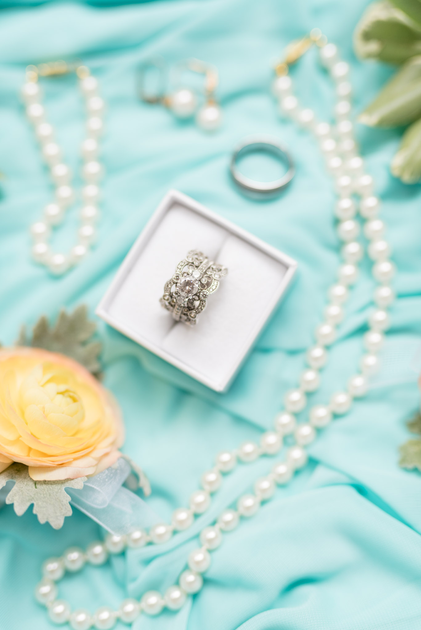 Wedding ring sits on spa blue bridesmaid dress.