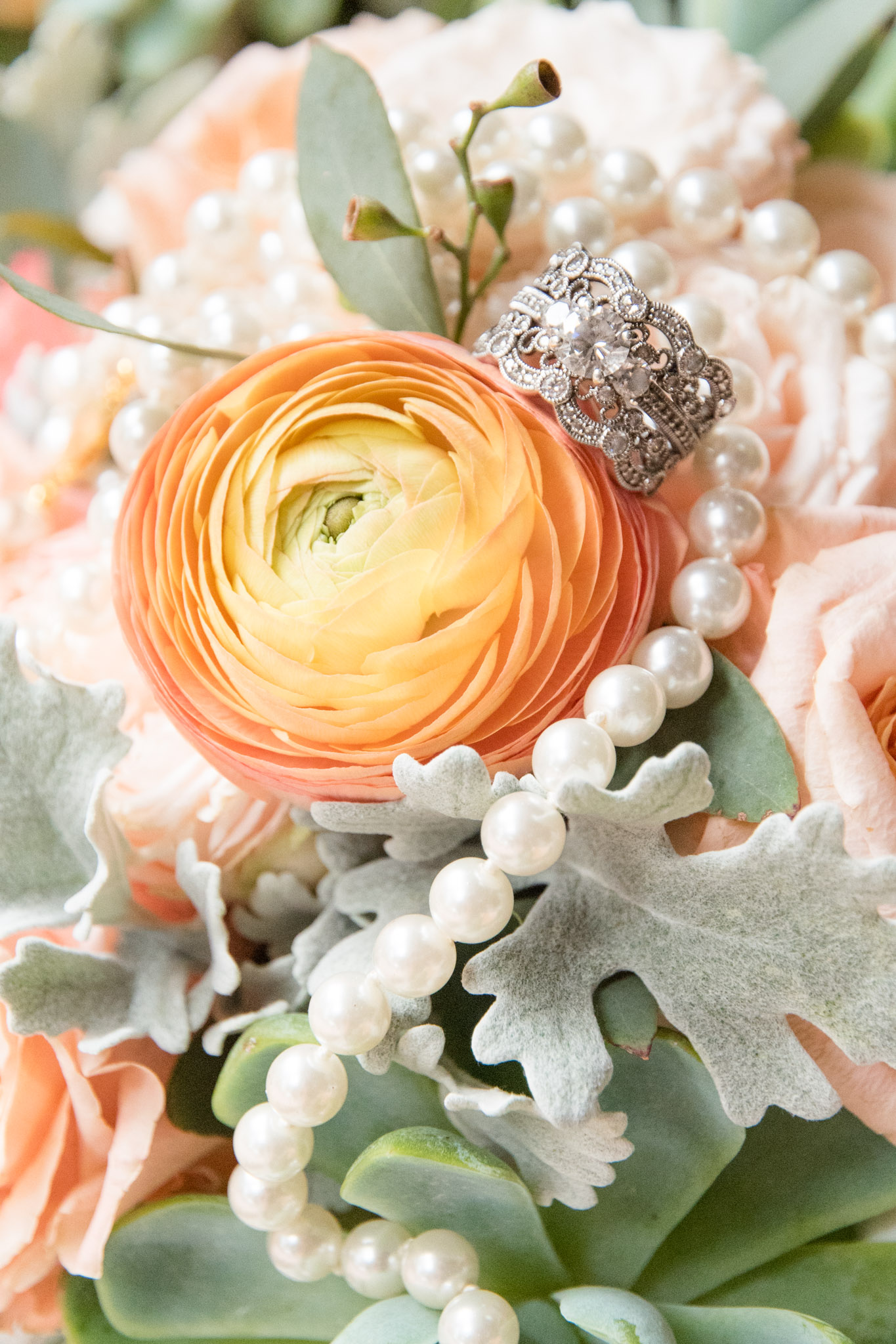 Engagement Ring and pearls sit on ranunculus.