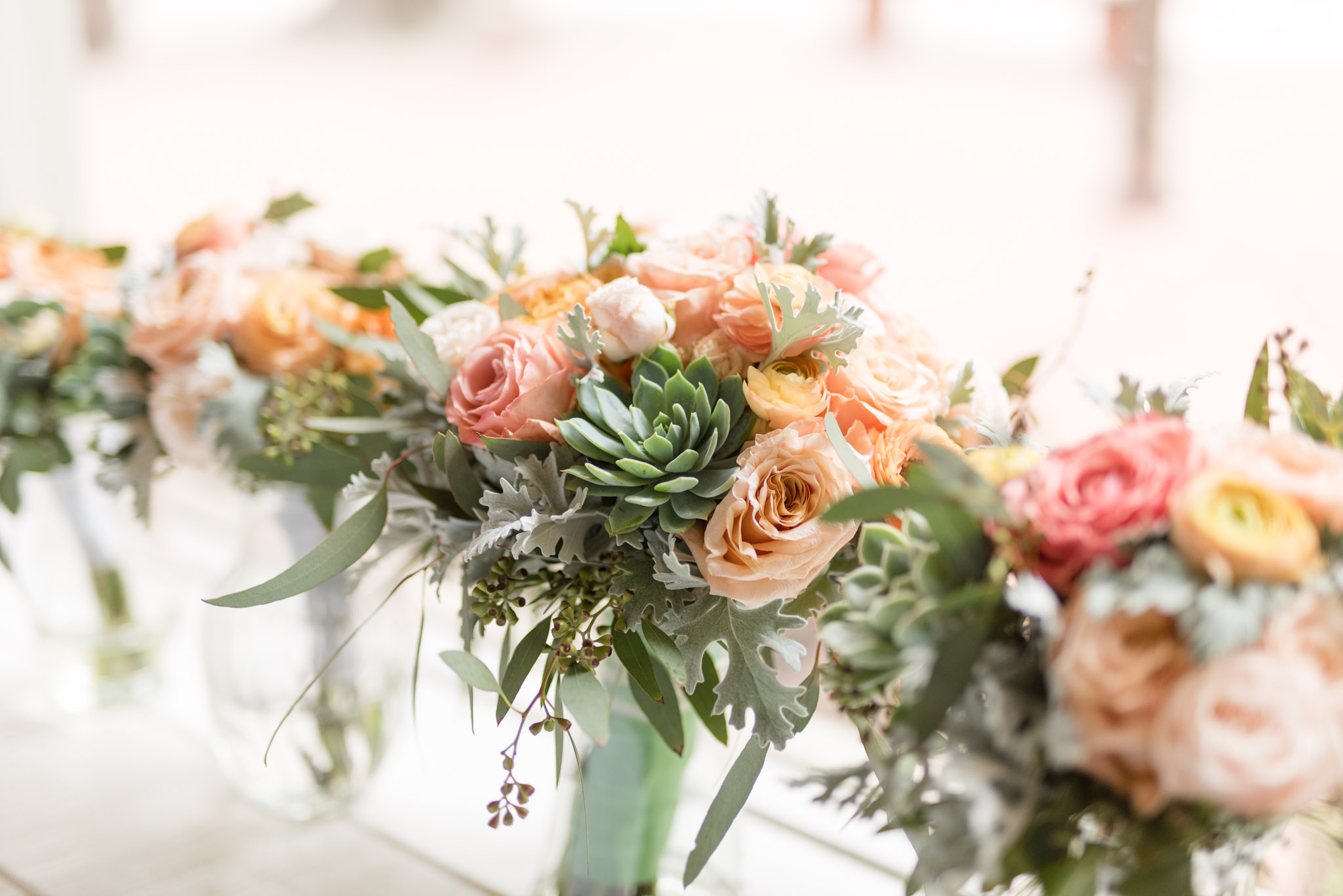 Wedding bouquets with succulents sit in vases.