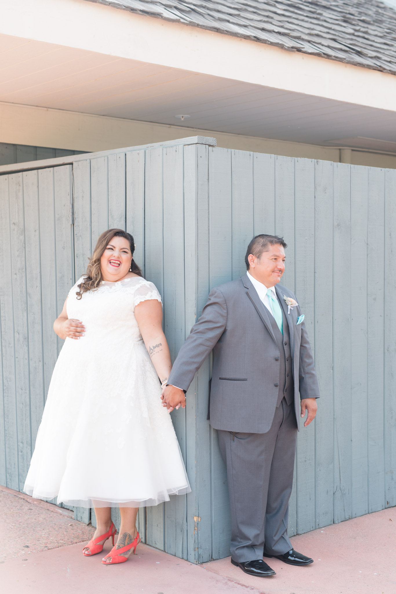 Bride and groom smile as they hold hands around the corner.