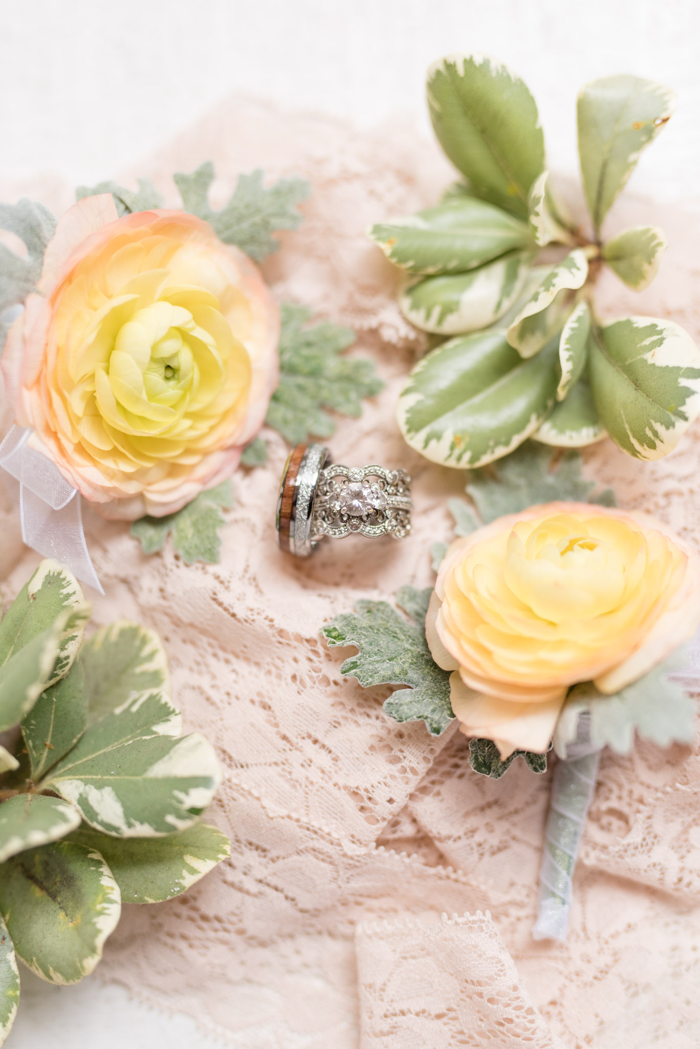 Wedding rings sit on pink lace with flowers.