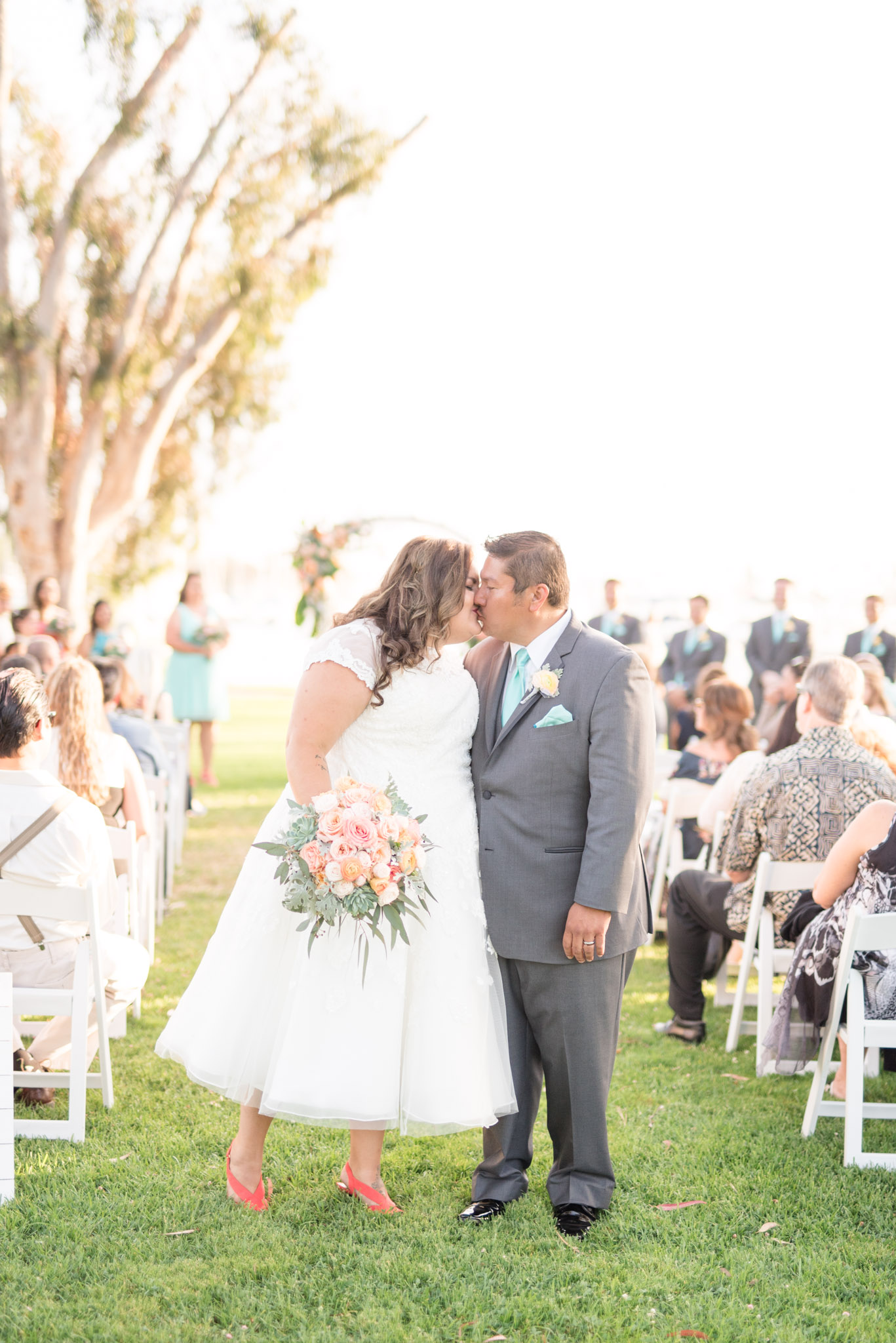 Bride and groom kiss at end of aisle after ceremony.