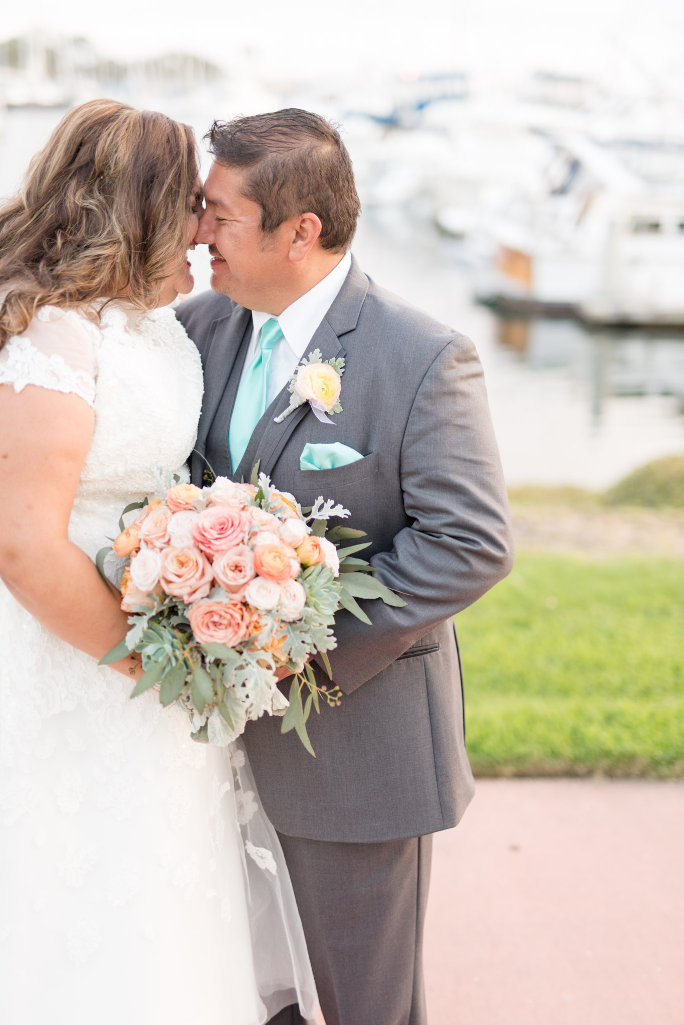 Bride and groom laugh while kissing.