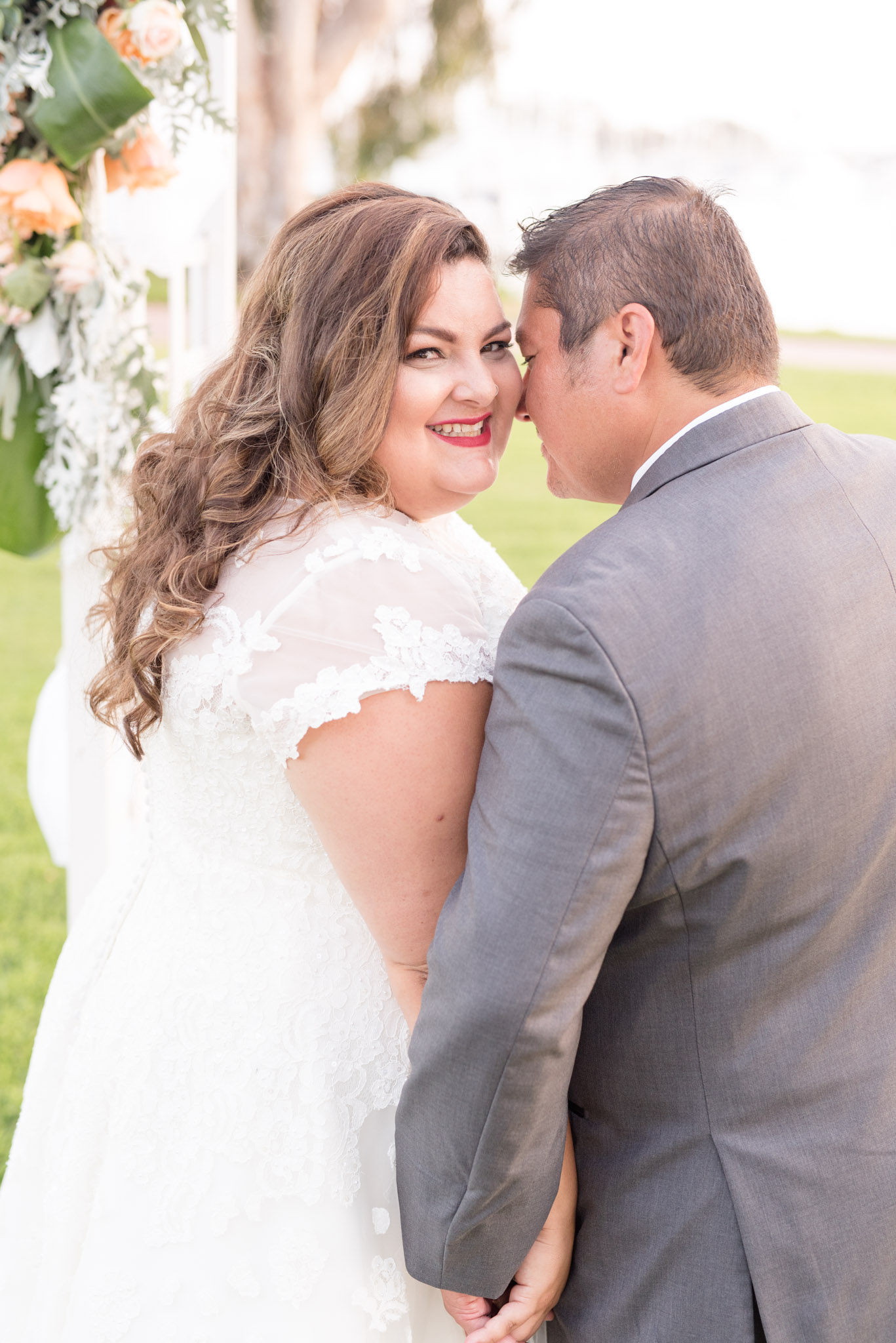 Bride smiles while groom snuggles.