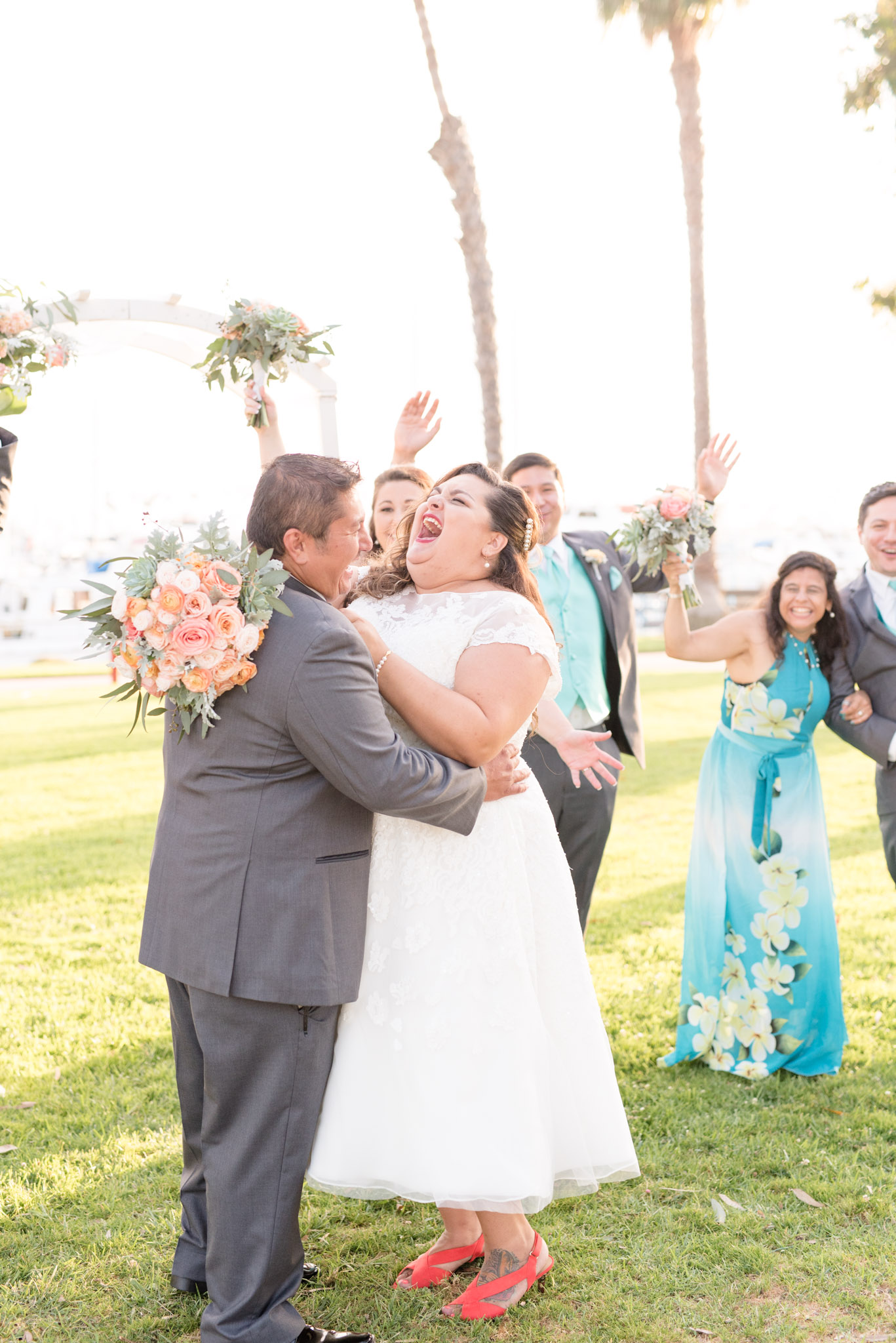 Bride and groom laugh with wedding party.