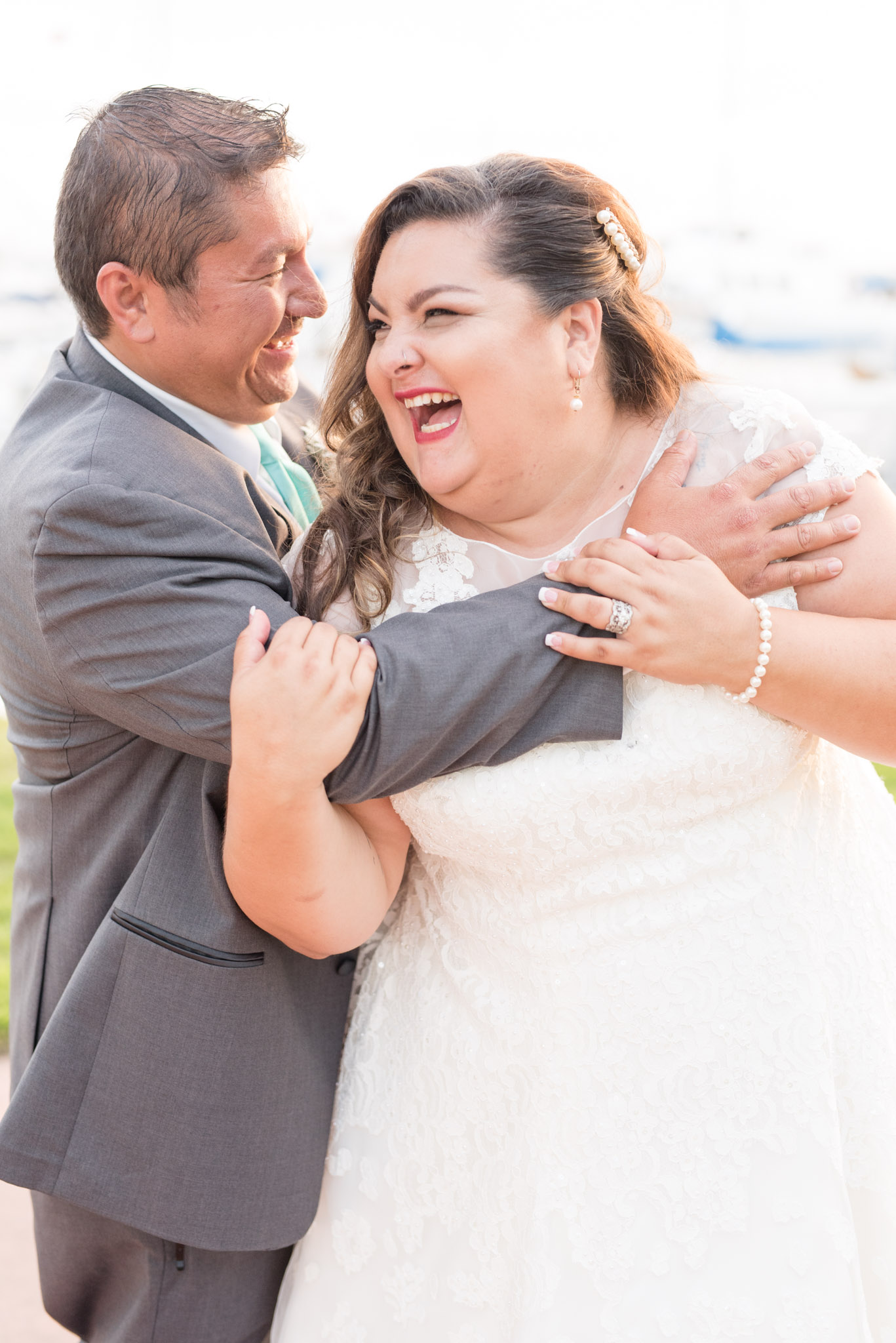 Groom hugs bride while they laugh.