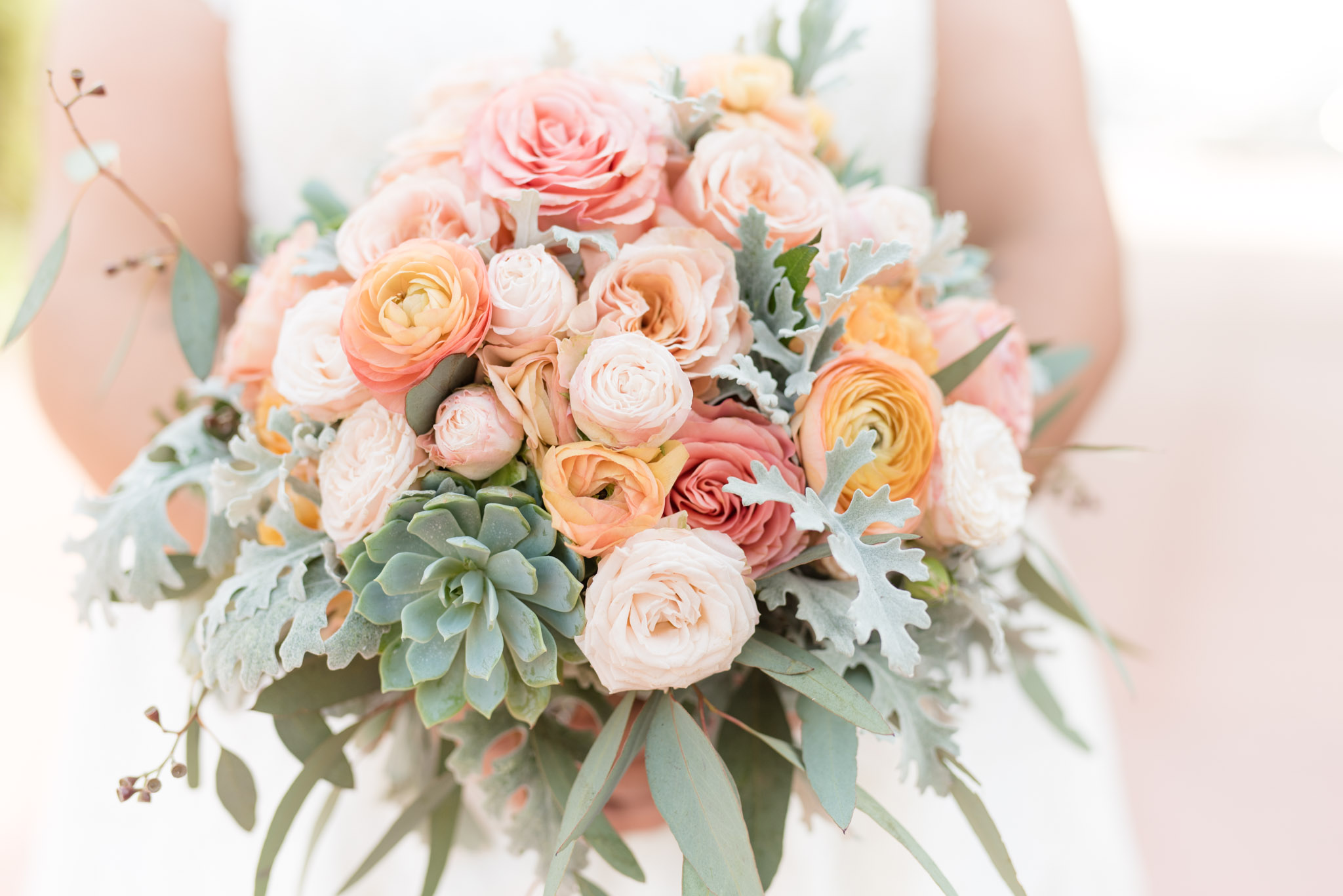 Wedding bouquet with ranunculus, succulents, and roses.