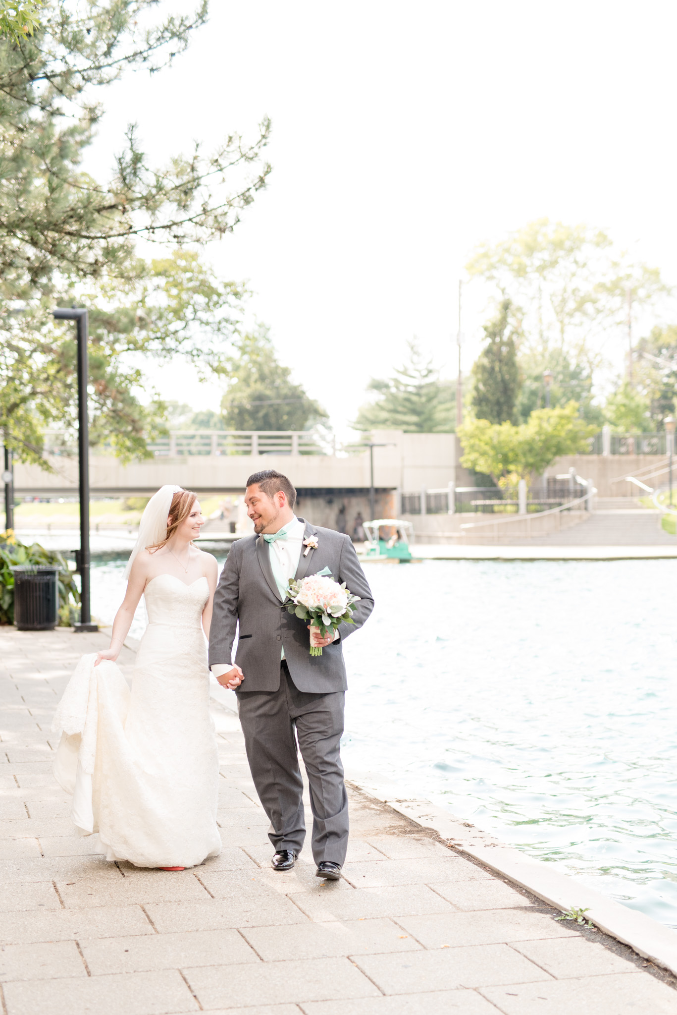 Bride and groom walk along Indianapolis canal.