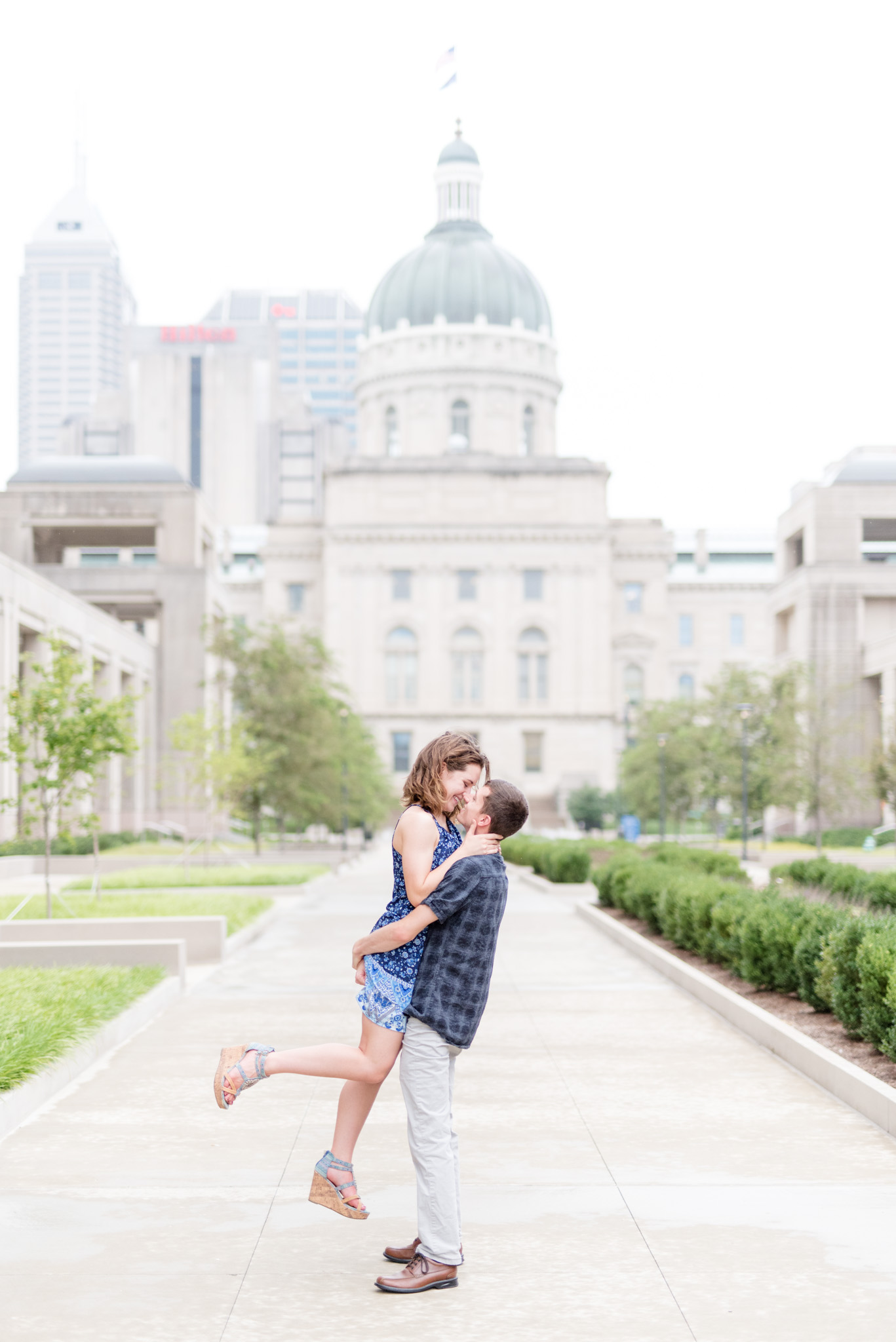 Guy lifts girl in front of Indiana Capital Building.