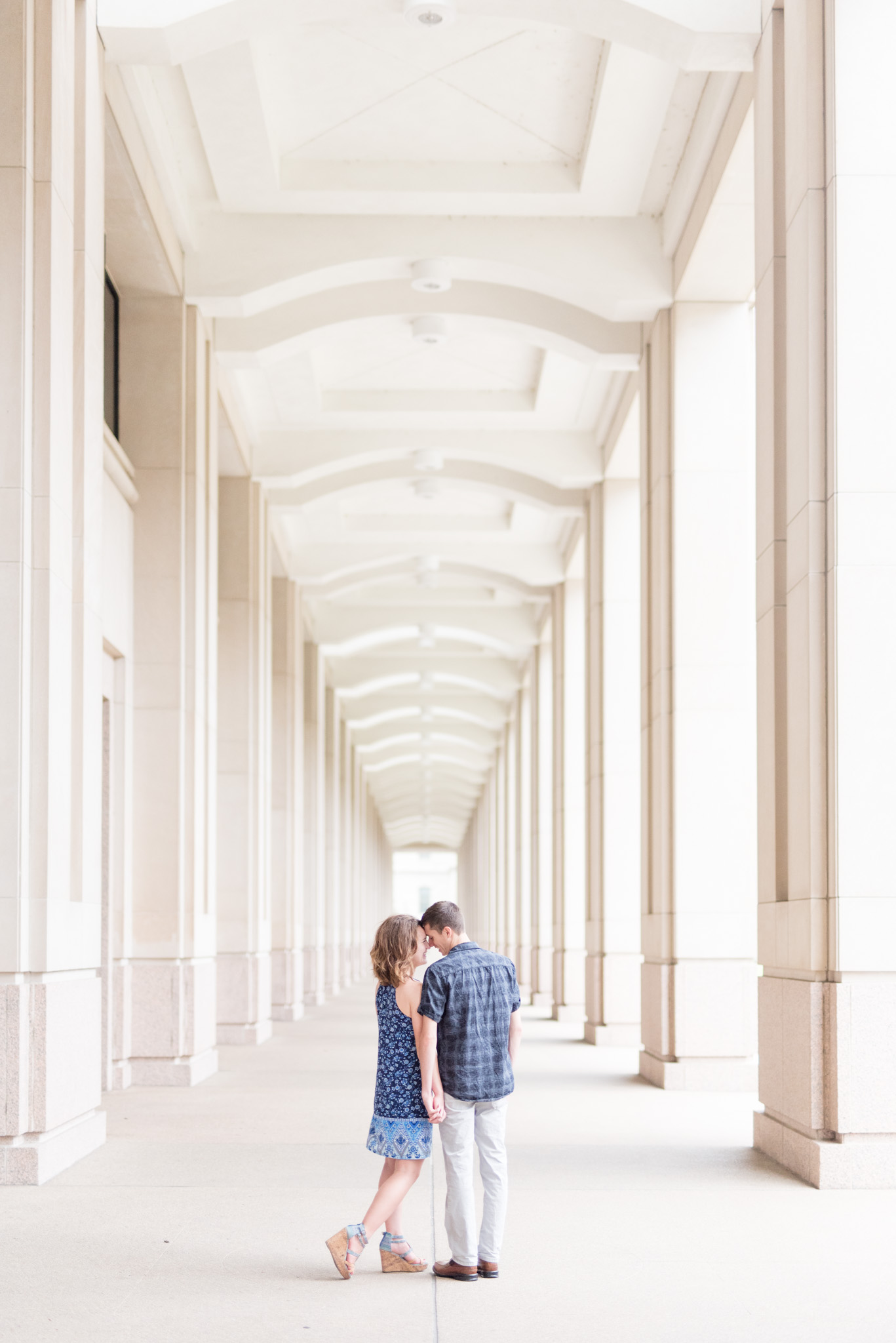 Couple leans in for kiss under columns.