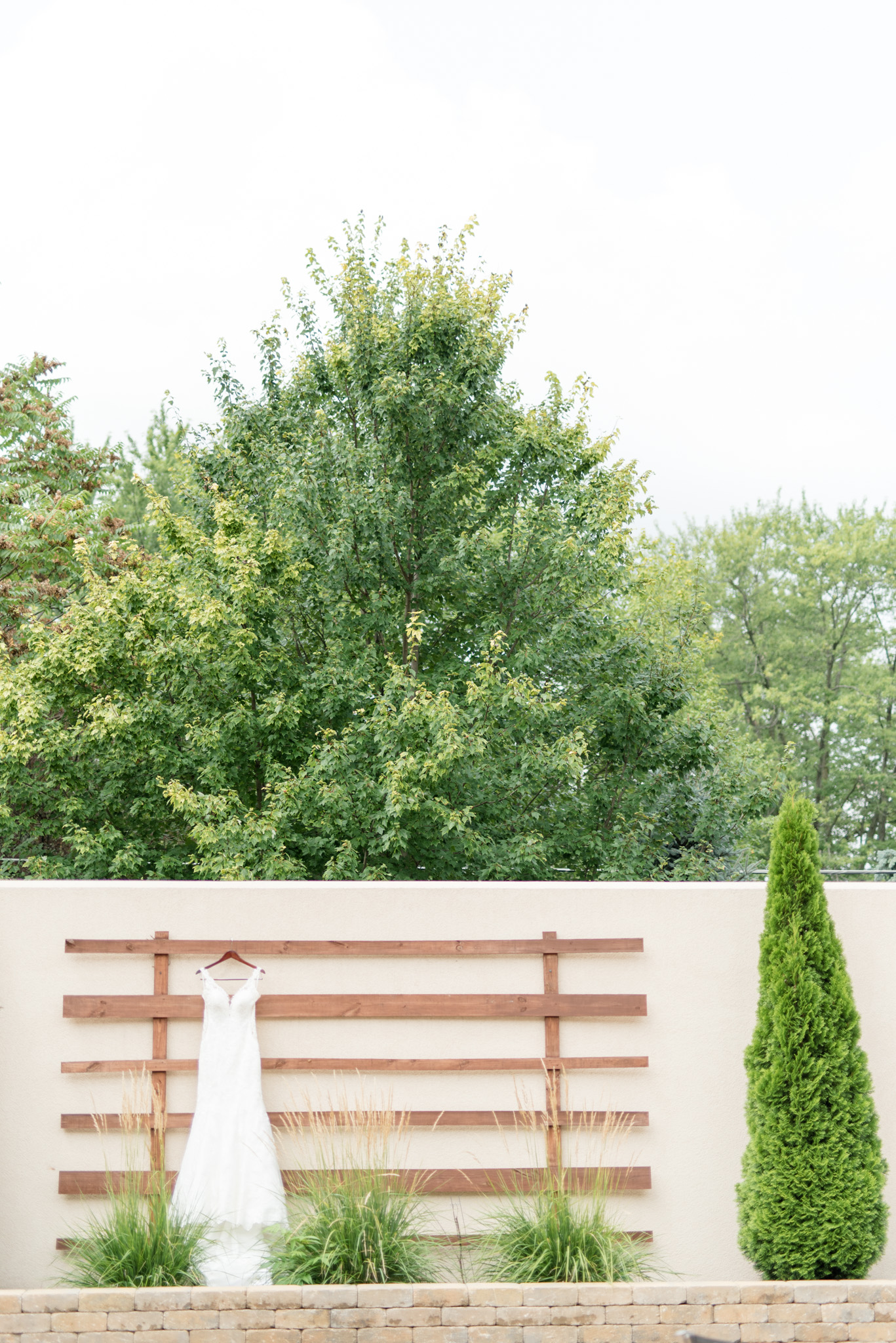 Wedding dress hangs on outside wall.