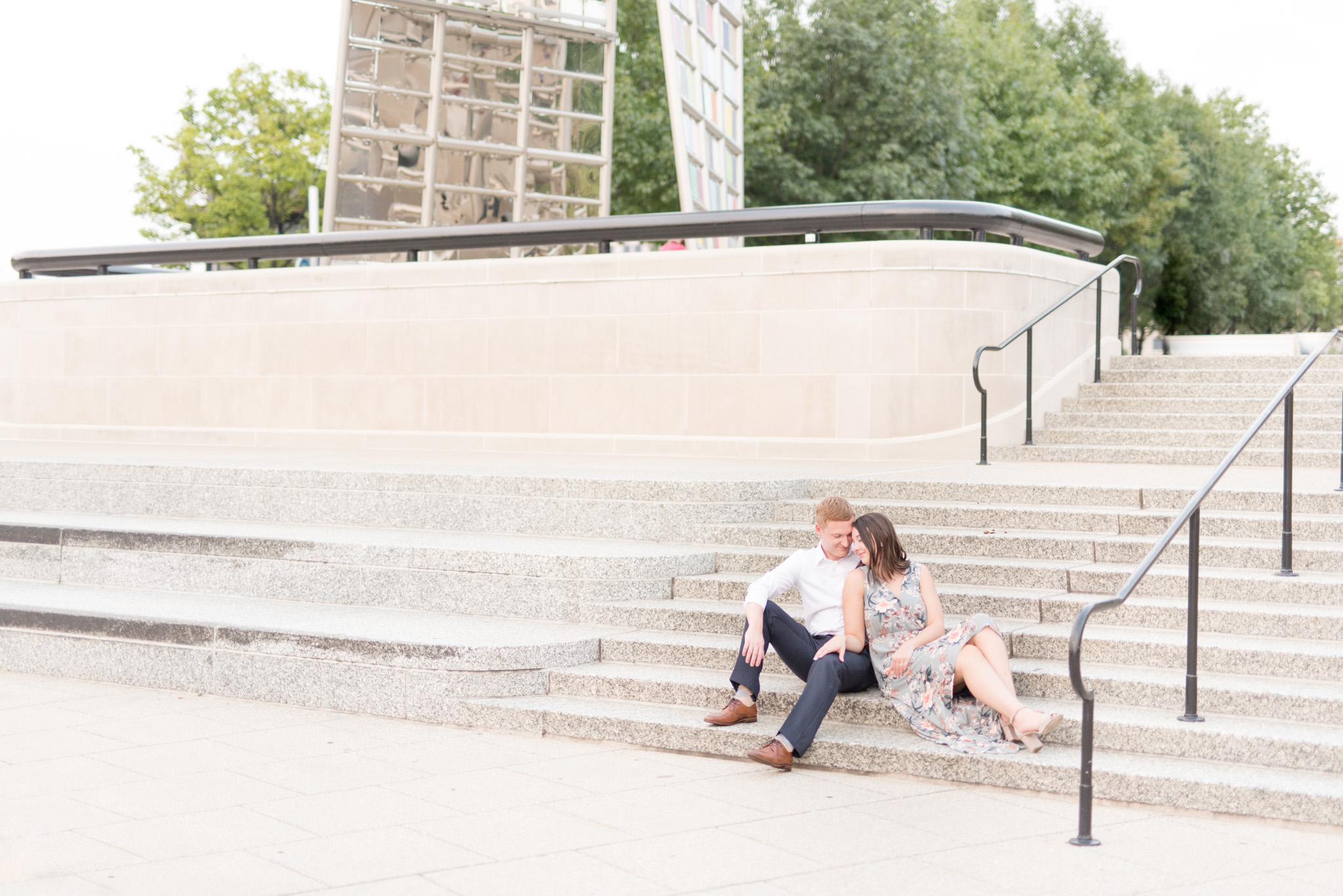 Engaged couple sits on stairway.