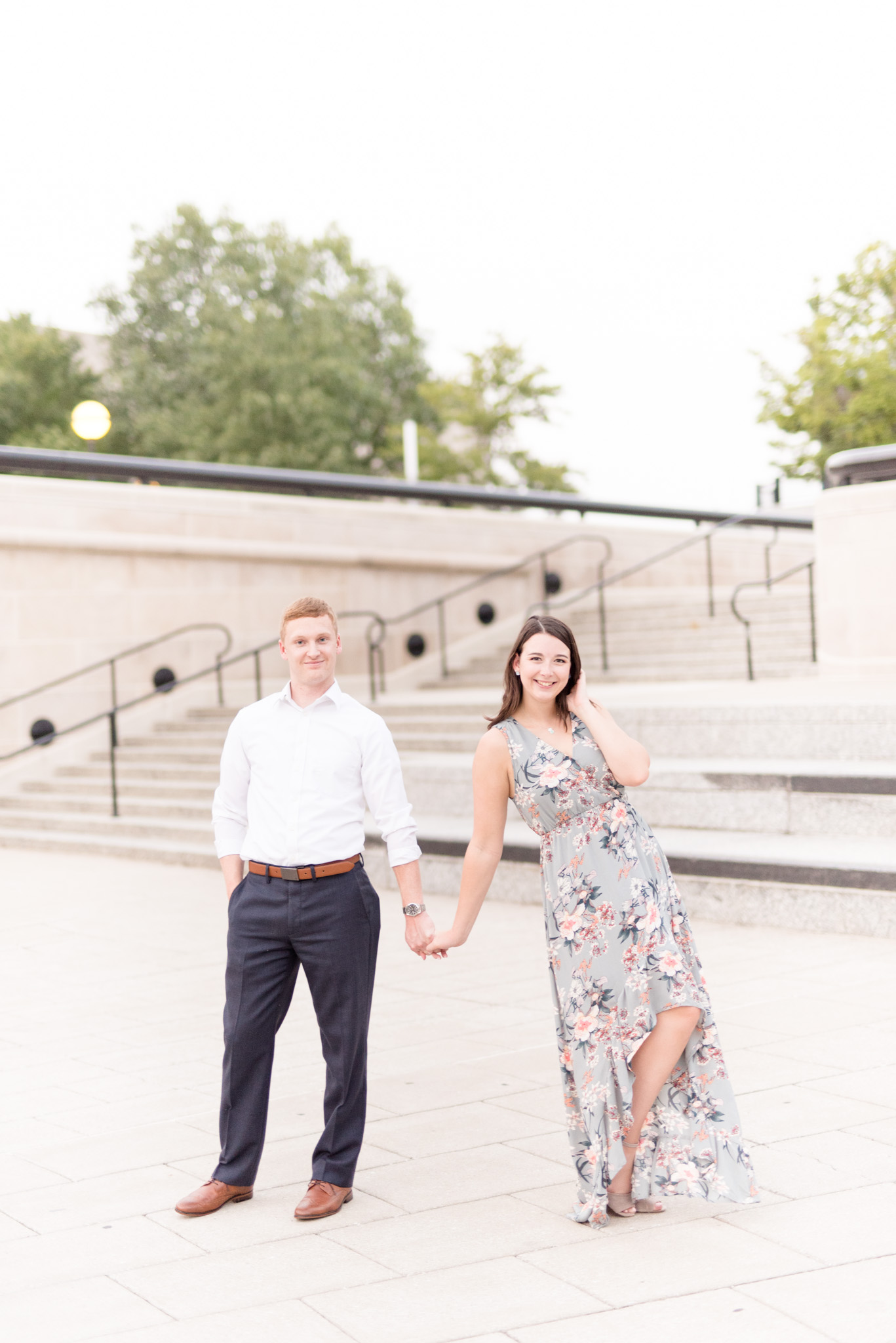 Engaged couple holds hands and smiles at camera.