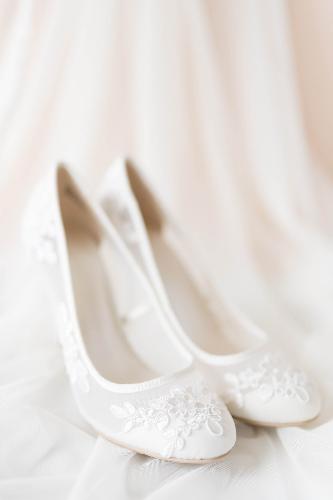 Bride's lace shoes sit on veil.