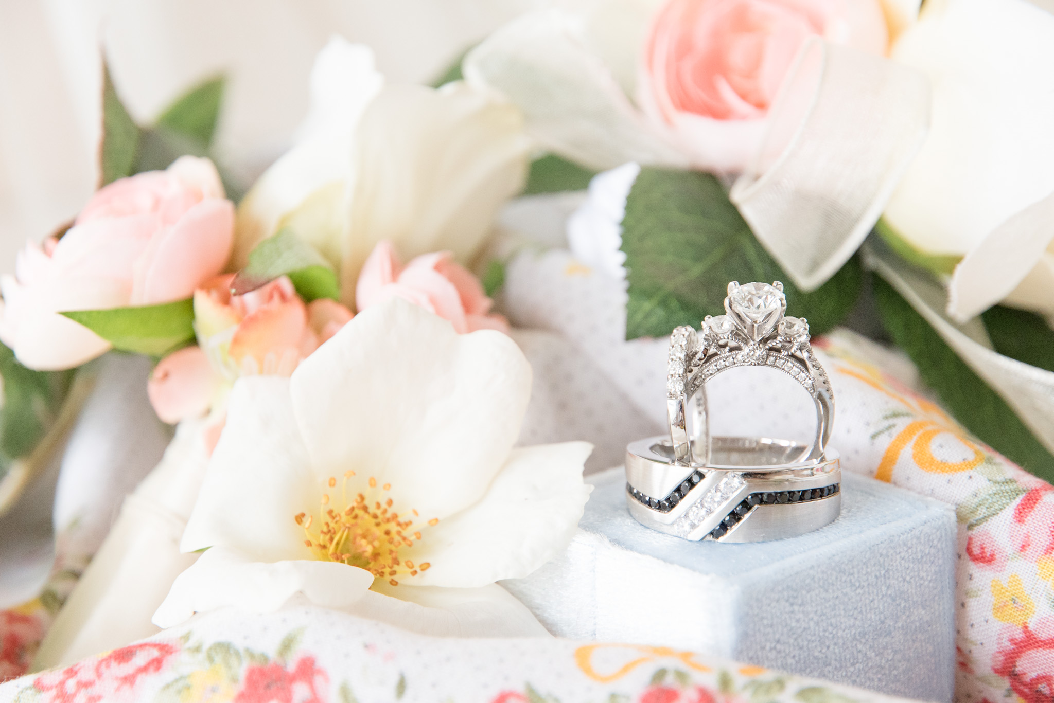 Intricate engagement ring sits in wedding rings