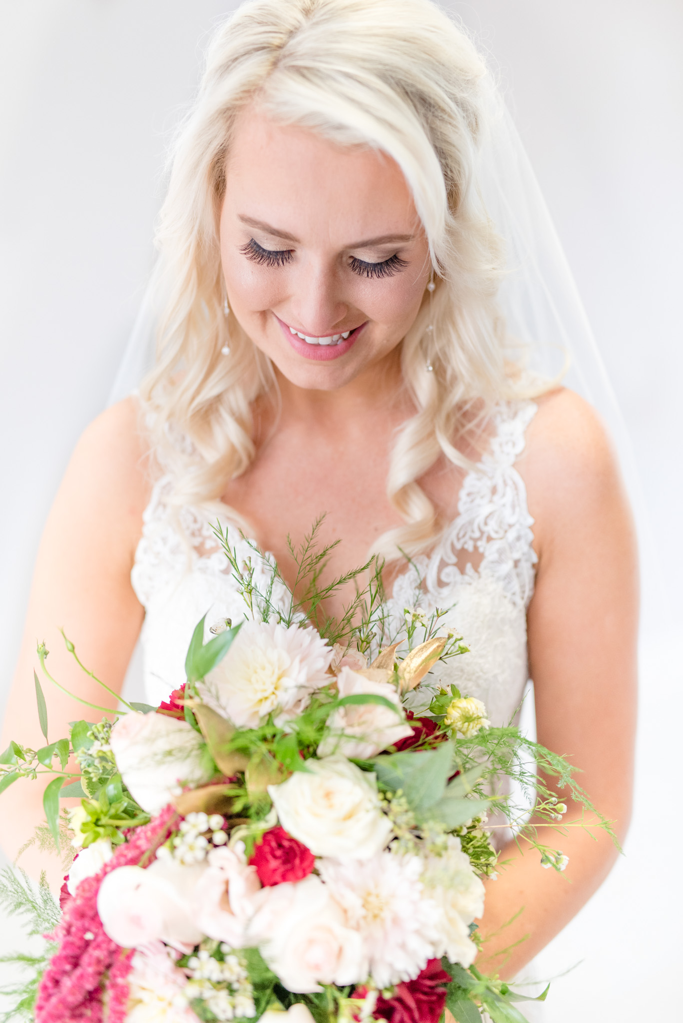 Bride looks down at bouquet.