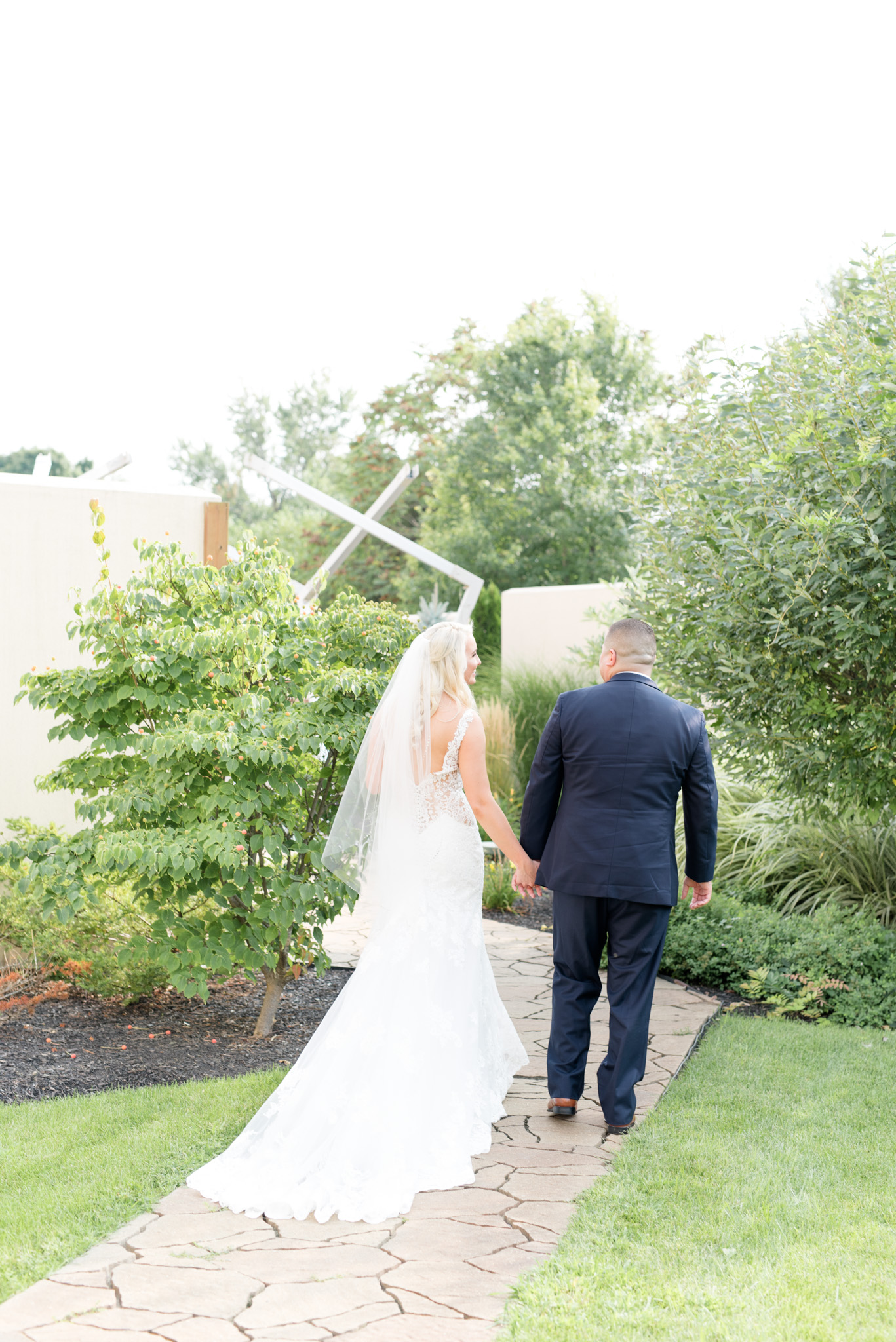 Bride and groom walk along path.