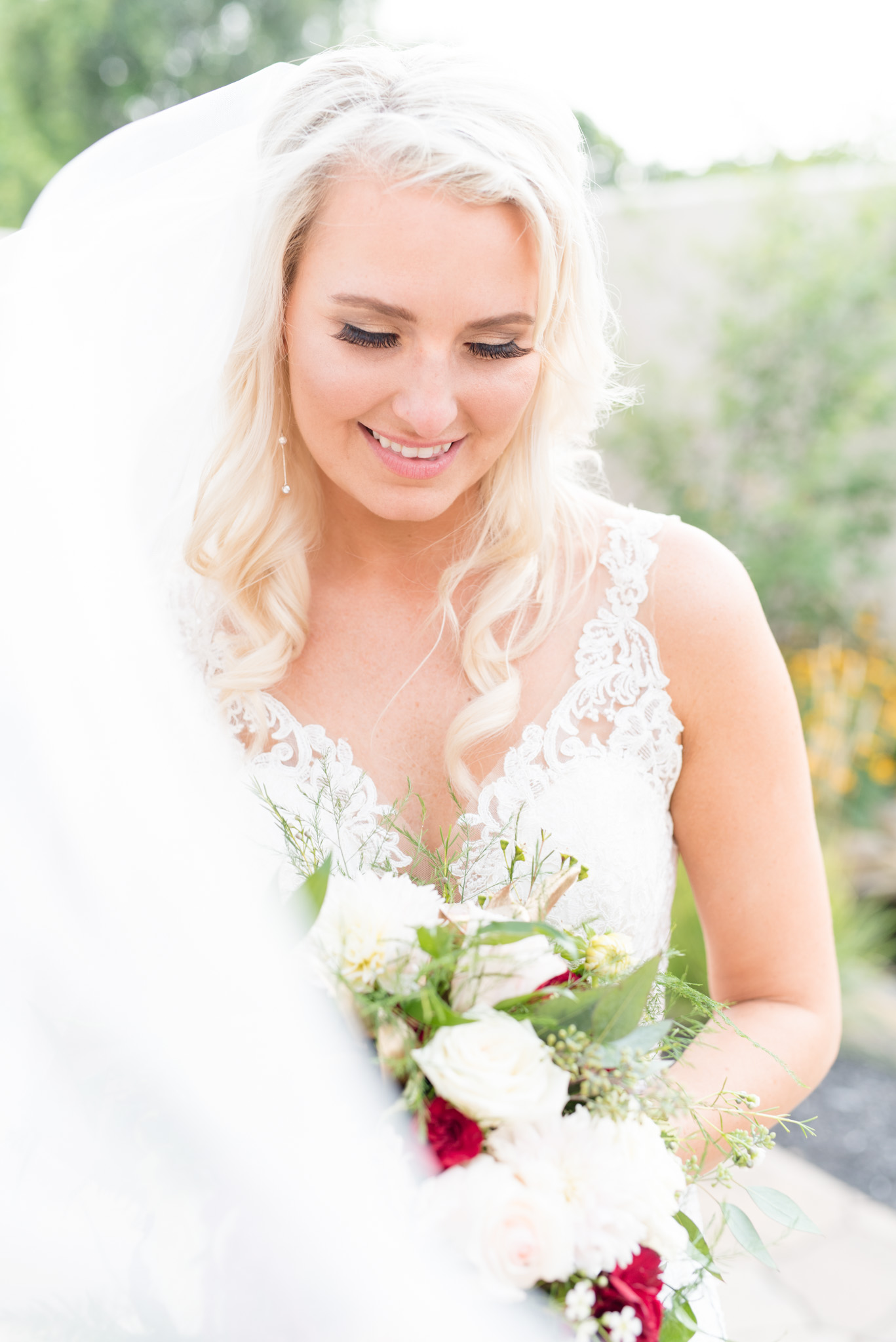 Bride looks down at bouquet and smiles.