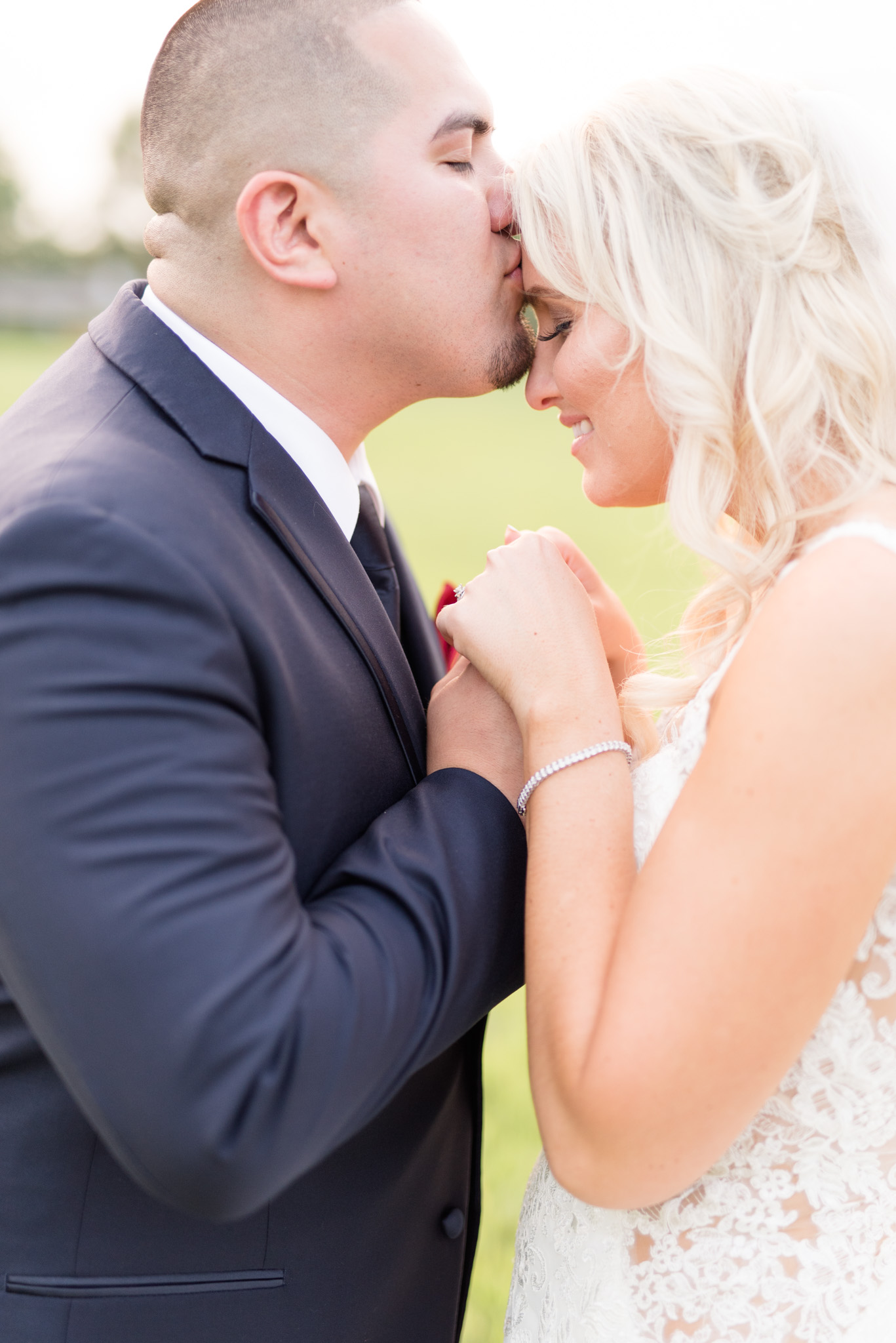 Groom kisses bride's forehead.