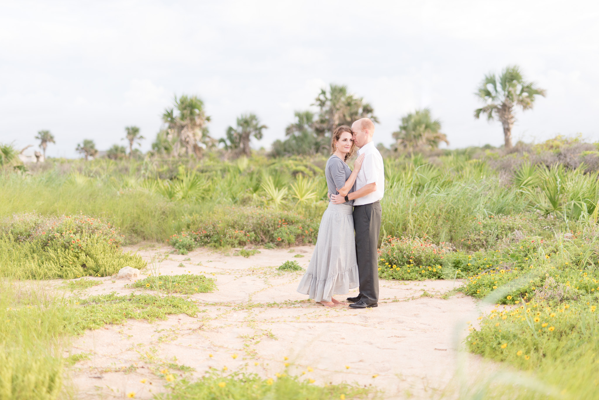 Husband and wife hug in palm grove.