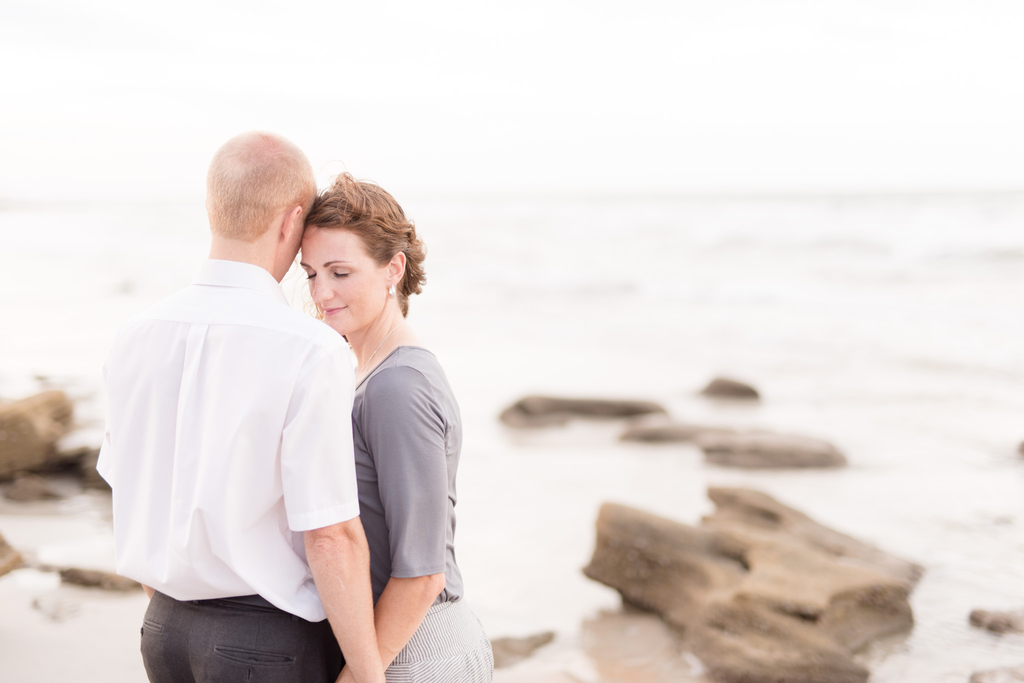 Couple snuggles on beach.