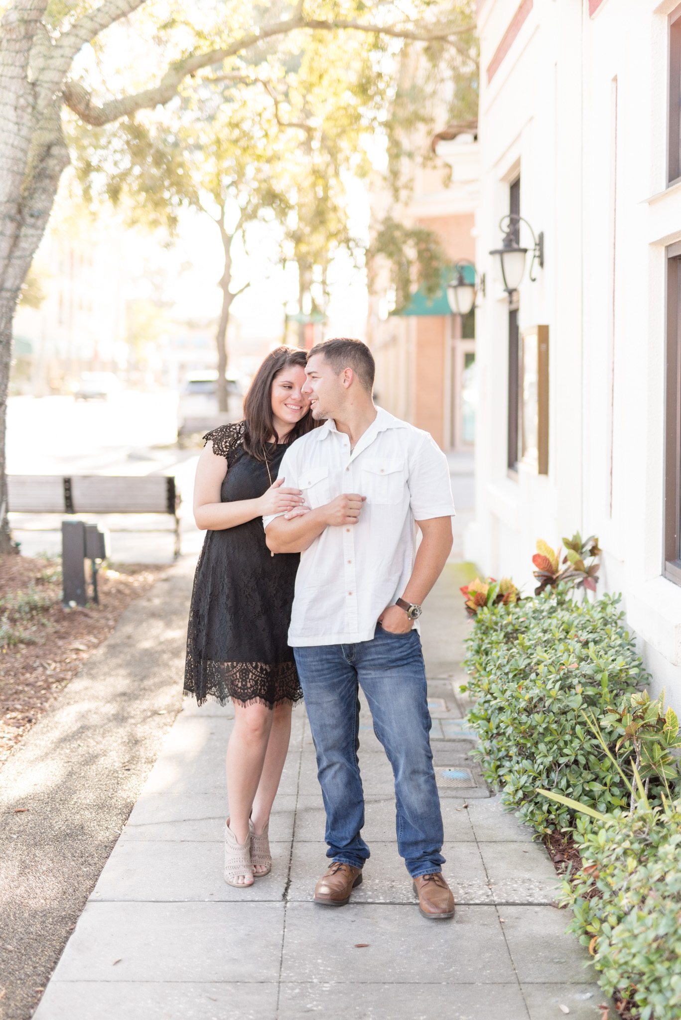 Engaged couple stands on downtown path.