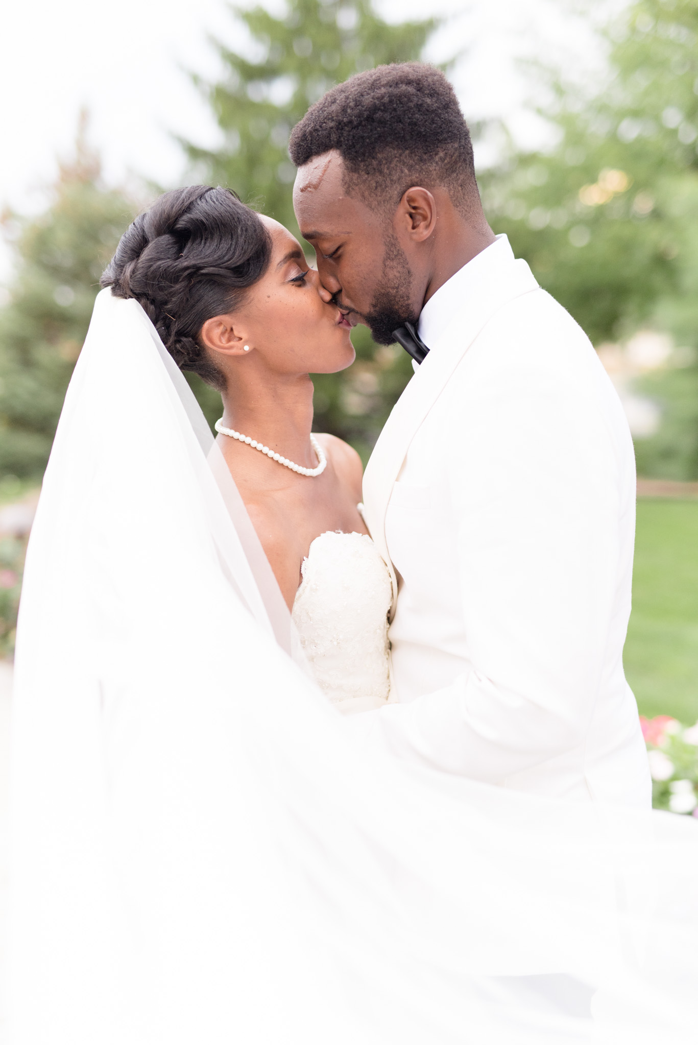 Bride and groom kiss with veil in front.