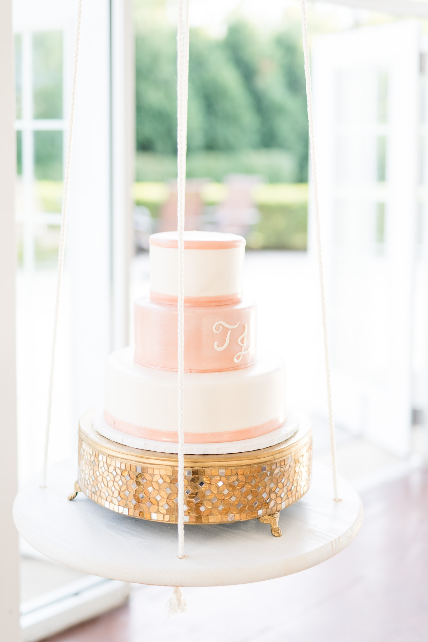 Wedding cake sits on hanging table.