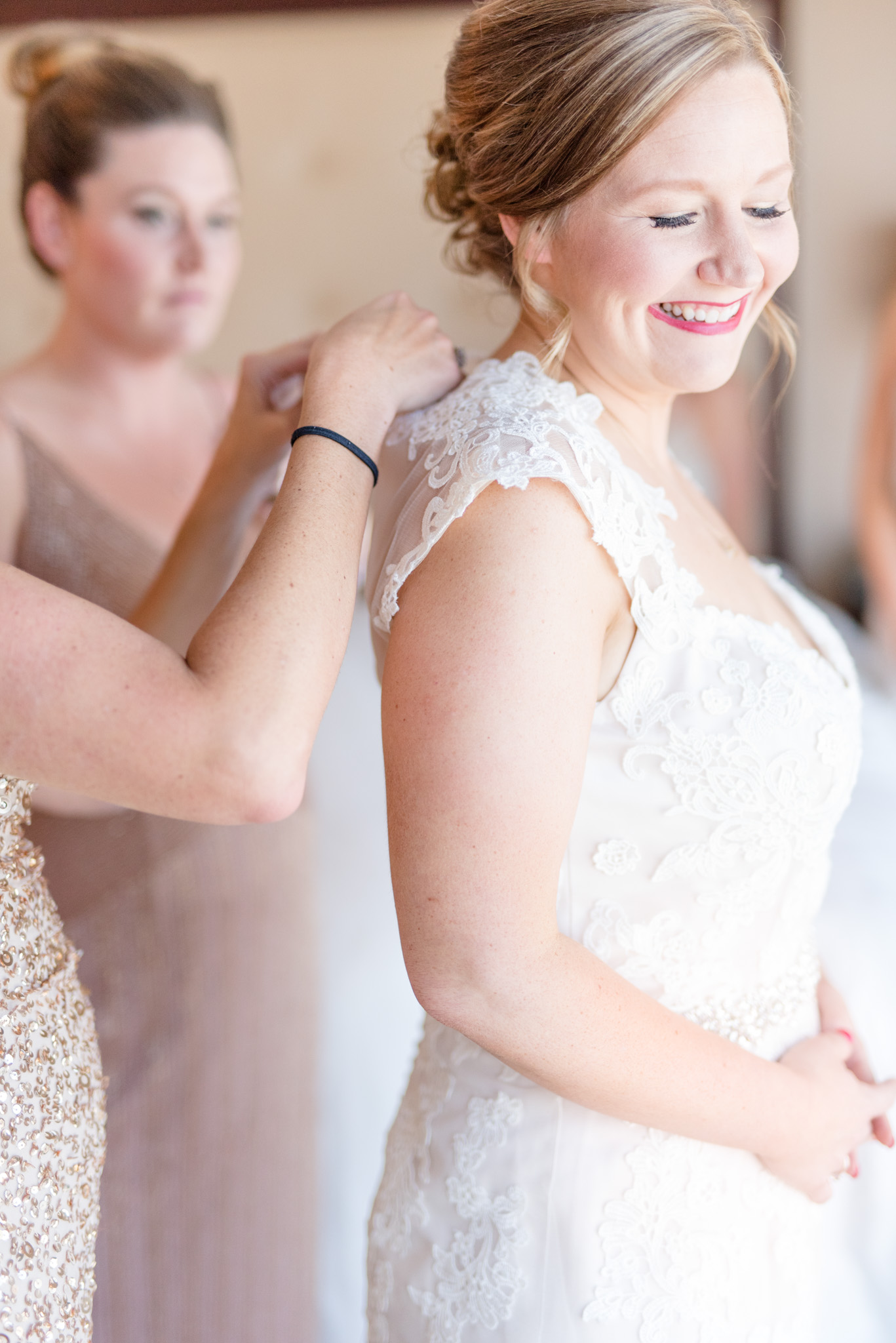 Bridesmaids help bride button dress.