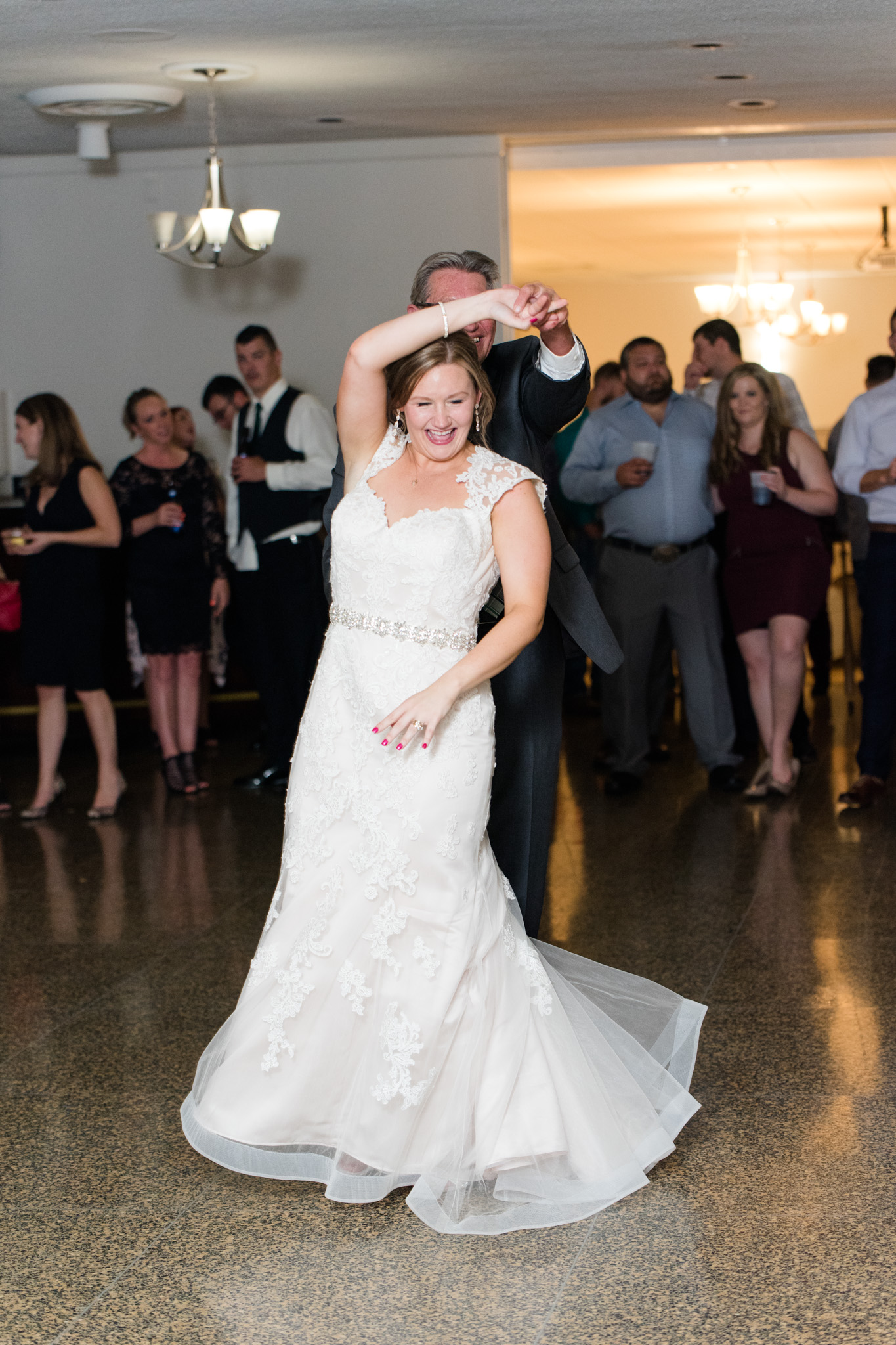 Father of bride twirls bride during reception.