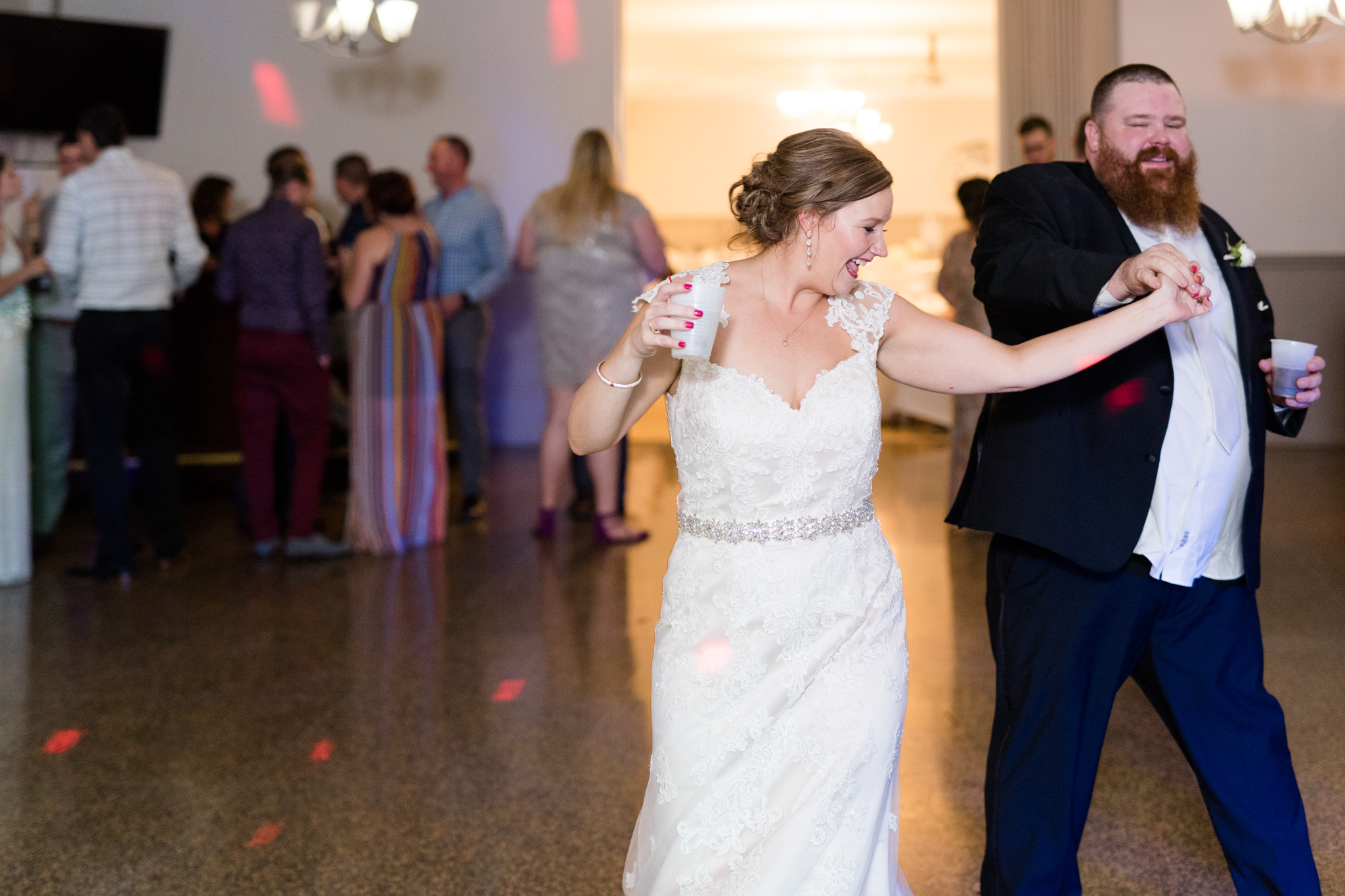 Groom twirls bride at wedding reception.