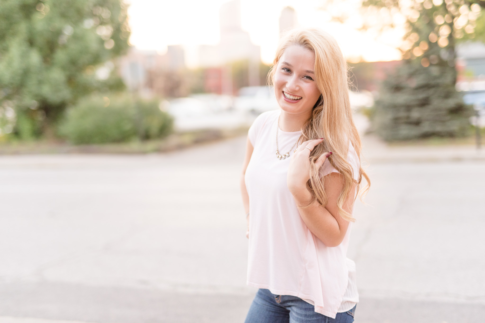 Senior girl laughs with city in distance.