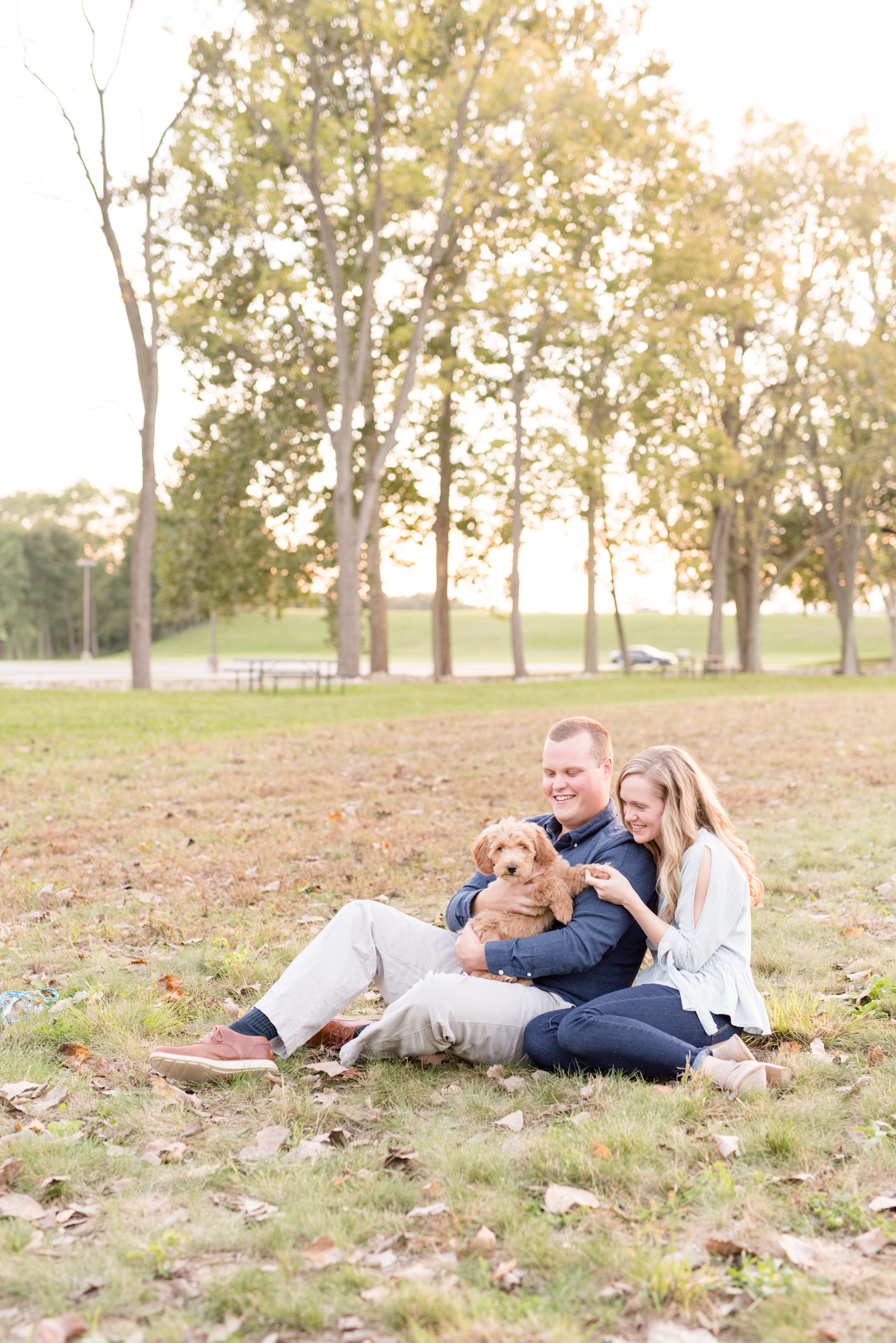 Couple holds puppy in field.