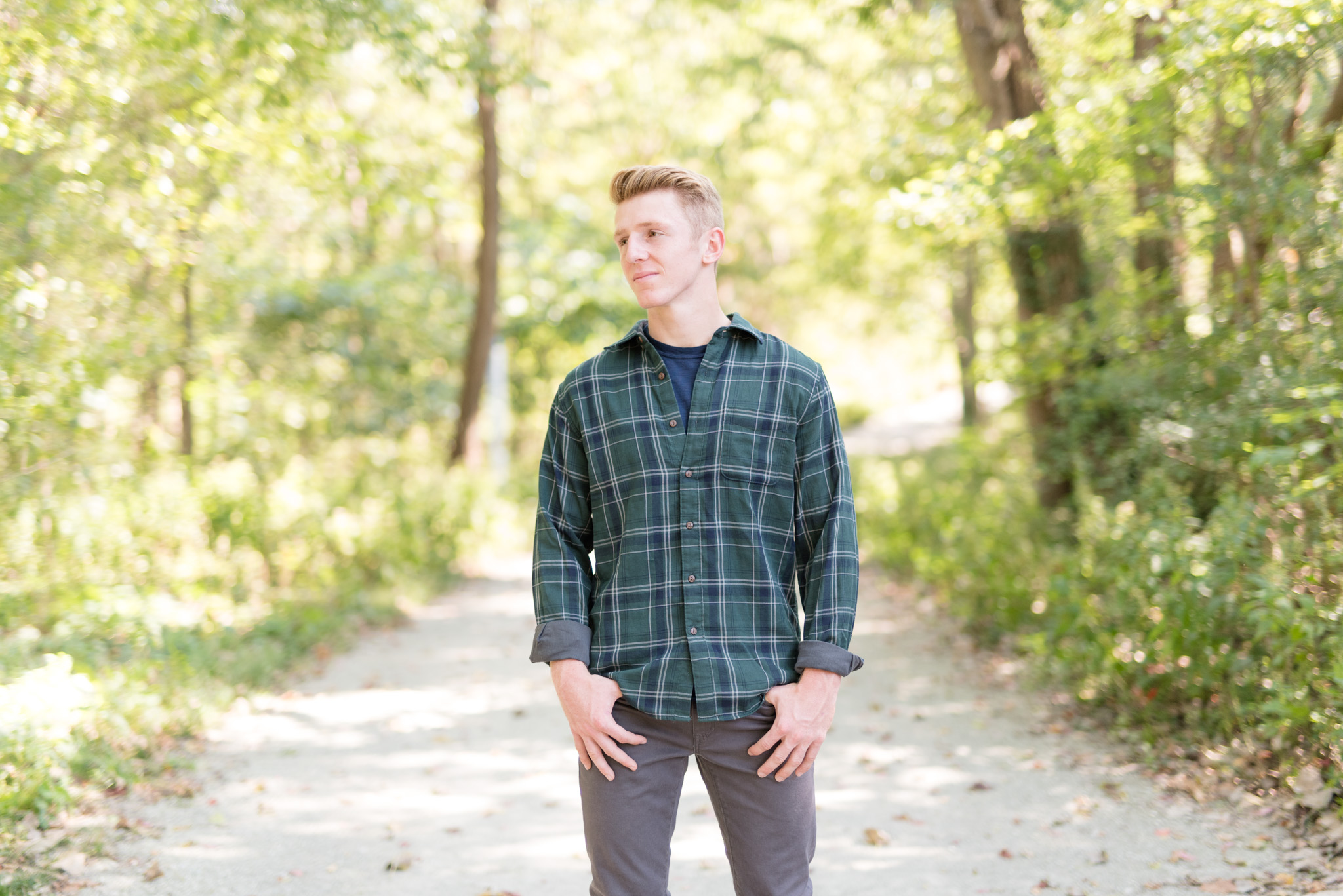 Guy stands on forest path and looks off to the side