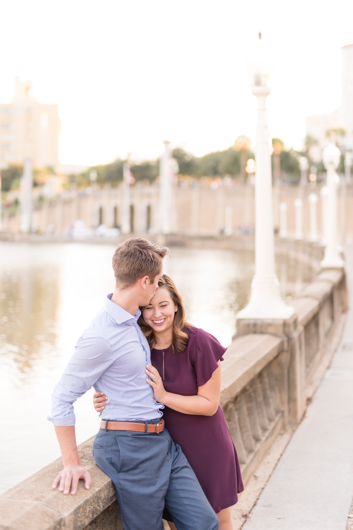 Couple cuddles at sunset by water.