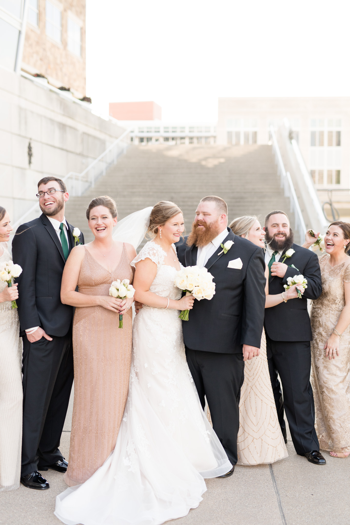 Bride and groom laugh while with wedding party.