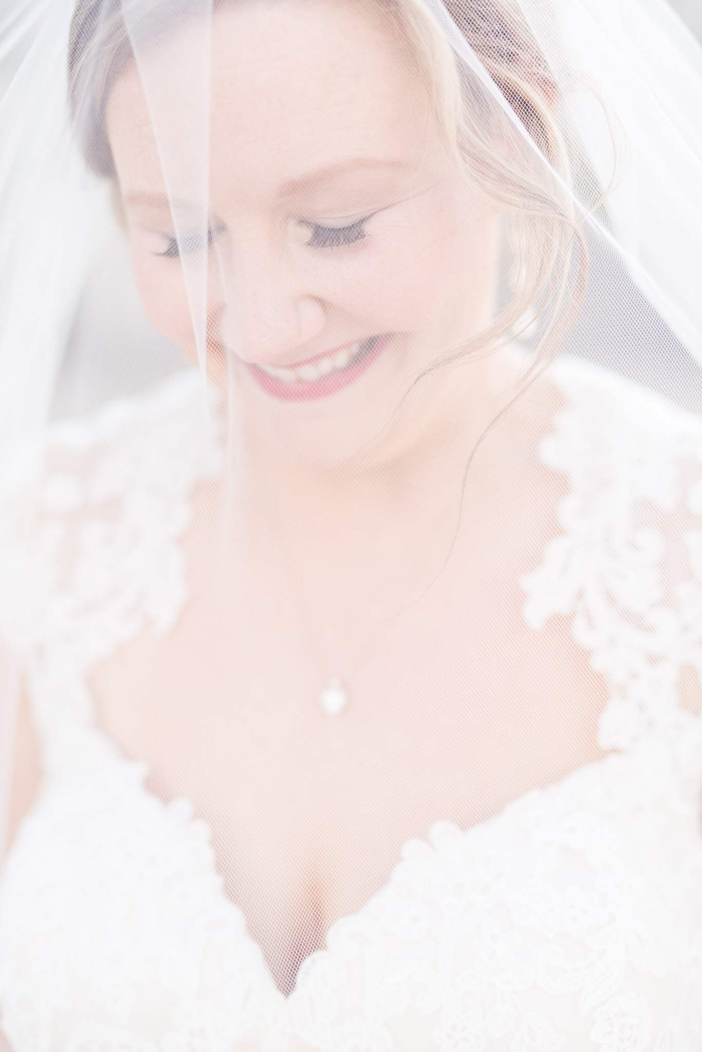 Bride looks down while under veil.