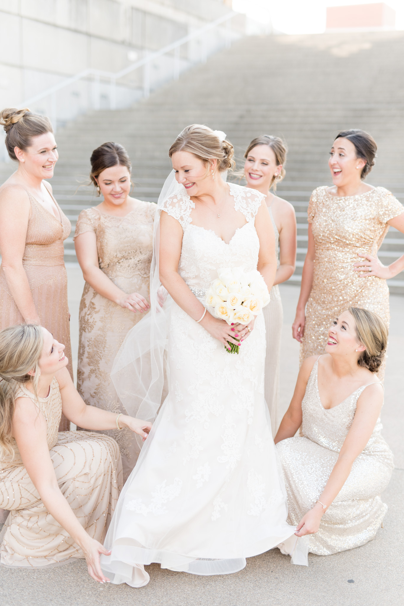 Bridesmaids help bride get ready and fluff dress.