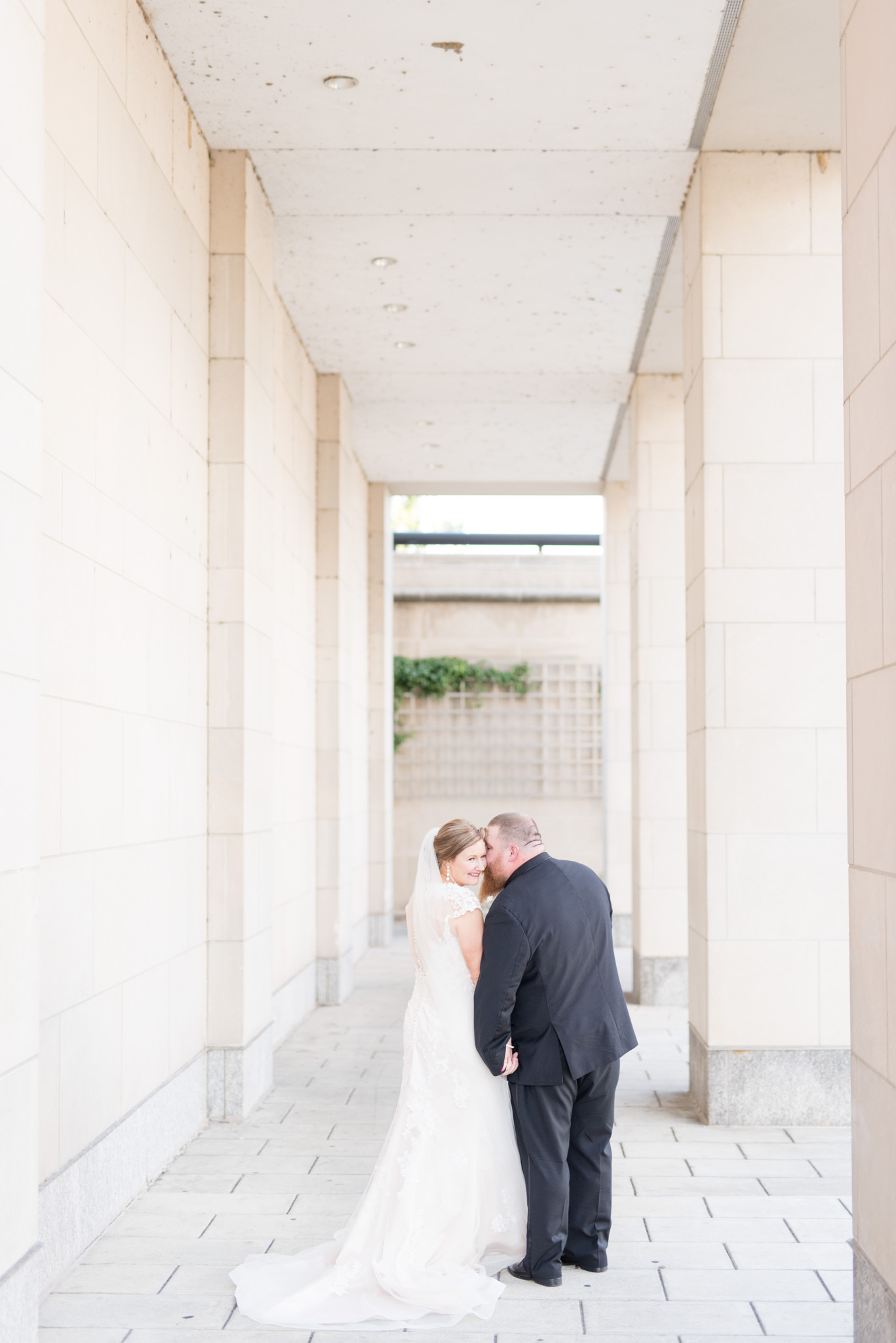 Bride and groom cuddle with cream columns.
