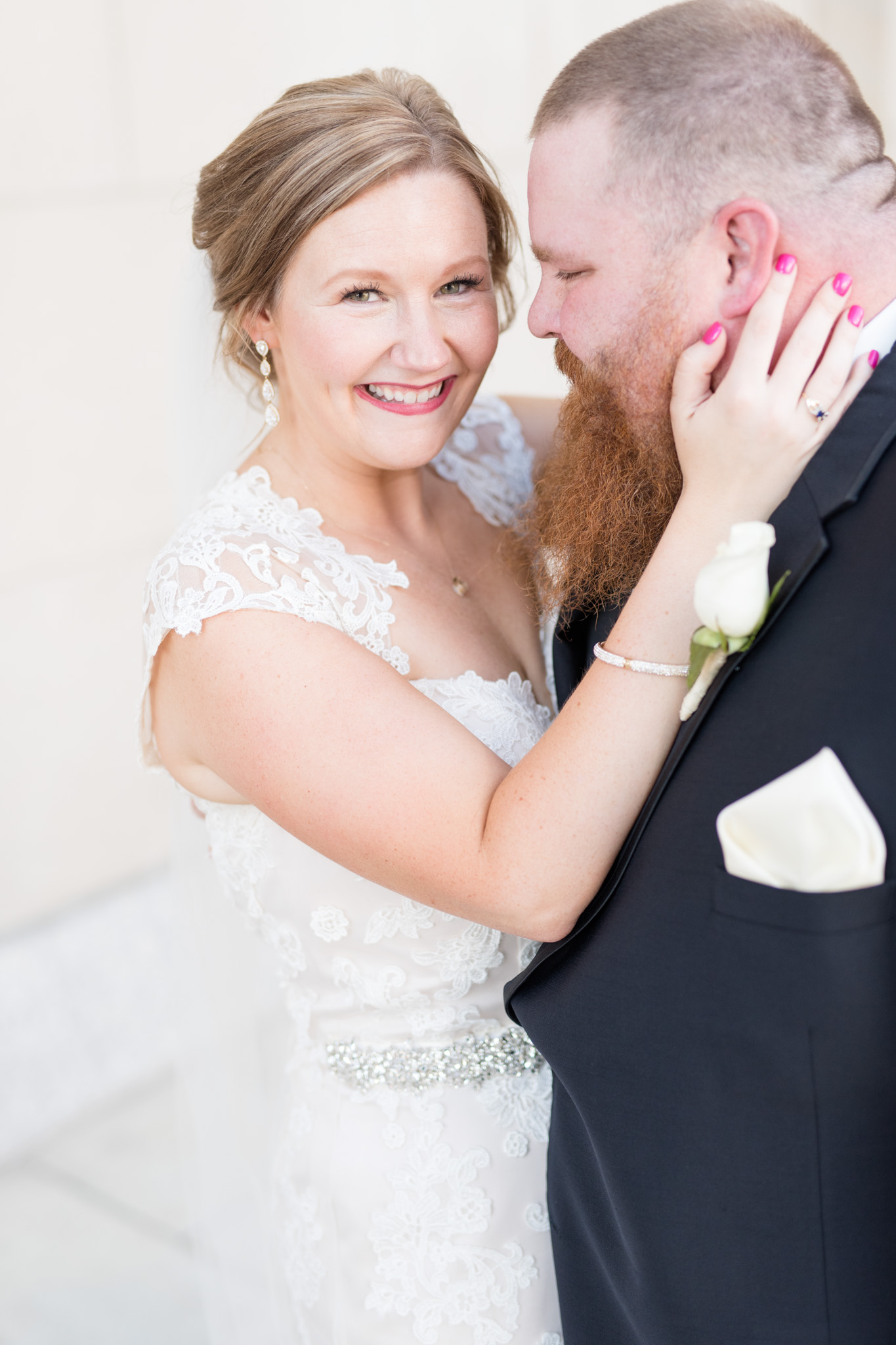 Bride smiles while groom looks at her.