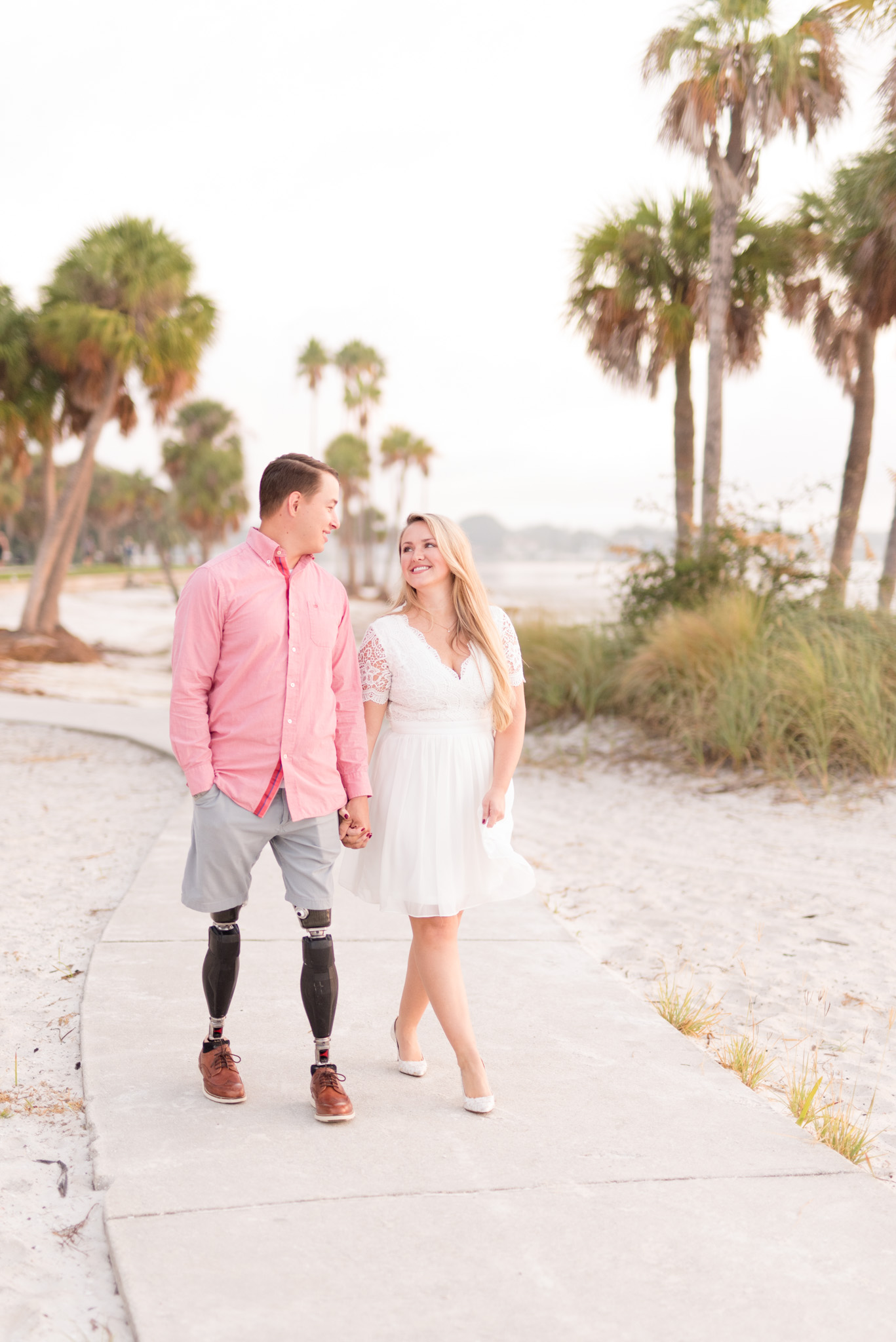 Couple walks down beach path holding hands.