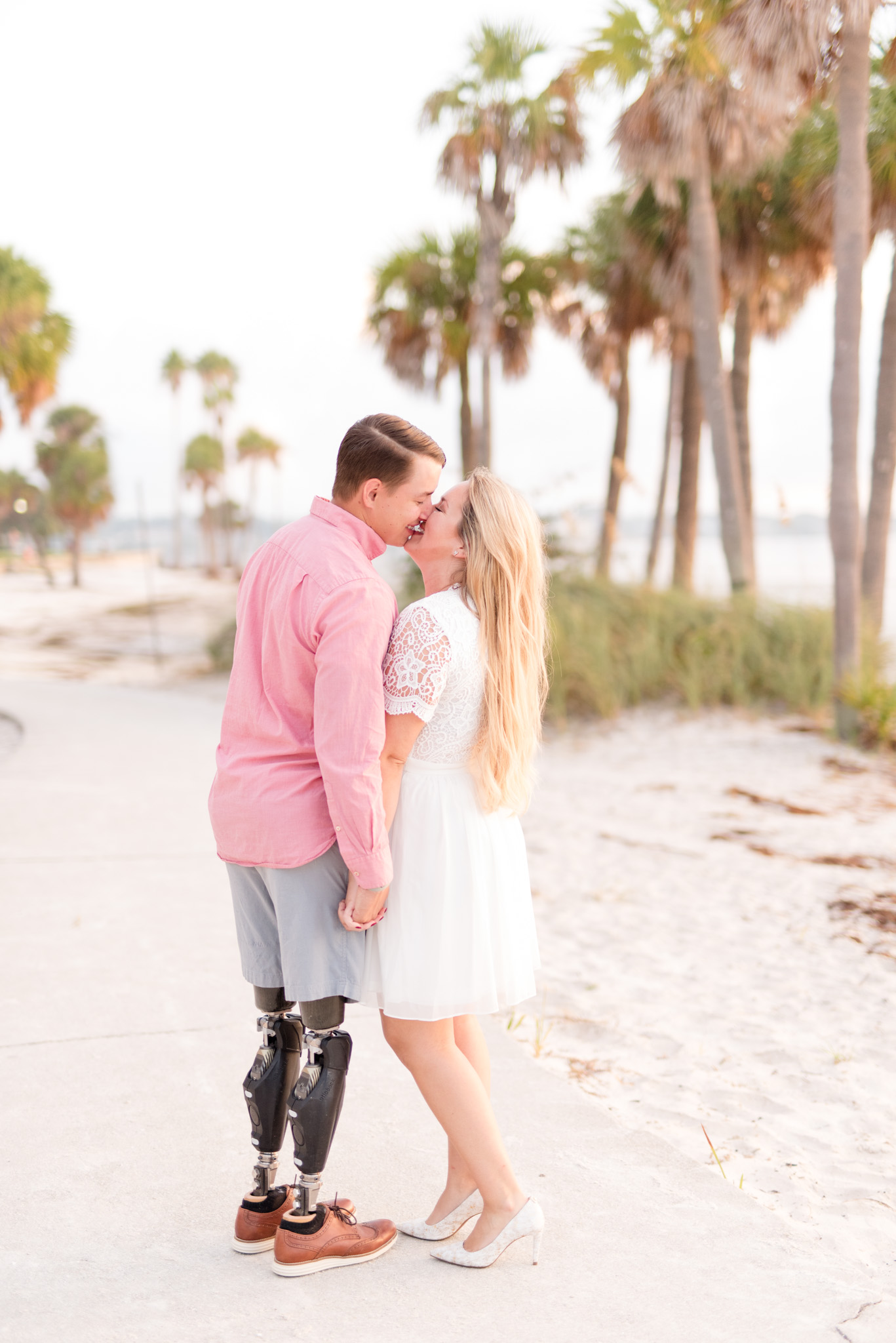 Couple holds hands and leans in for a kiss.