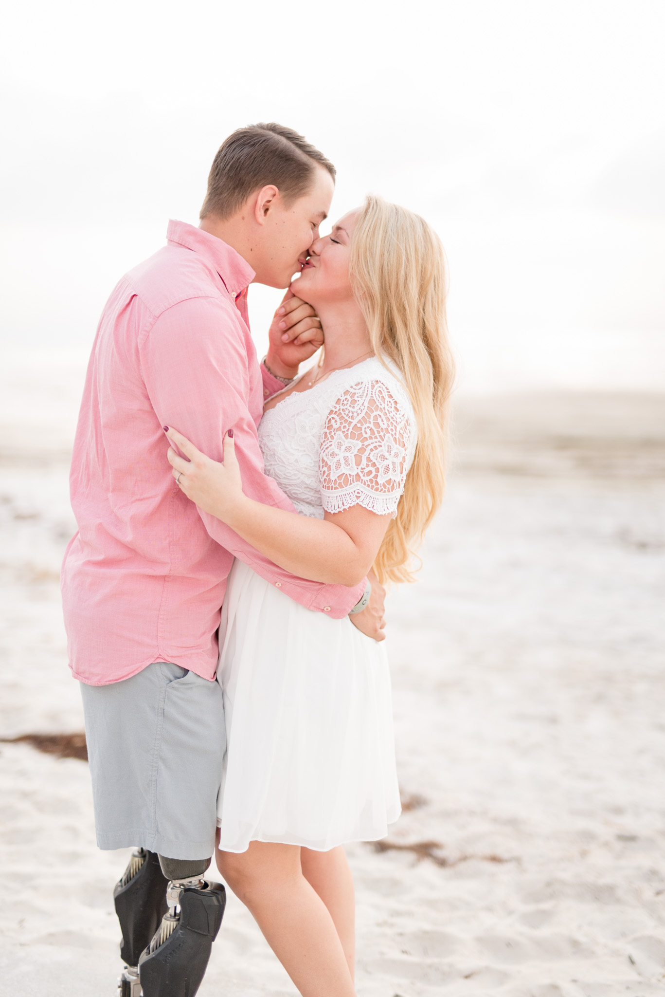 Couple kisses on beach.