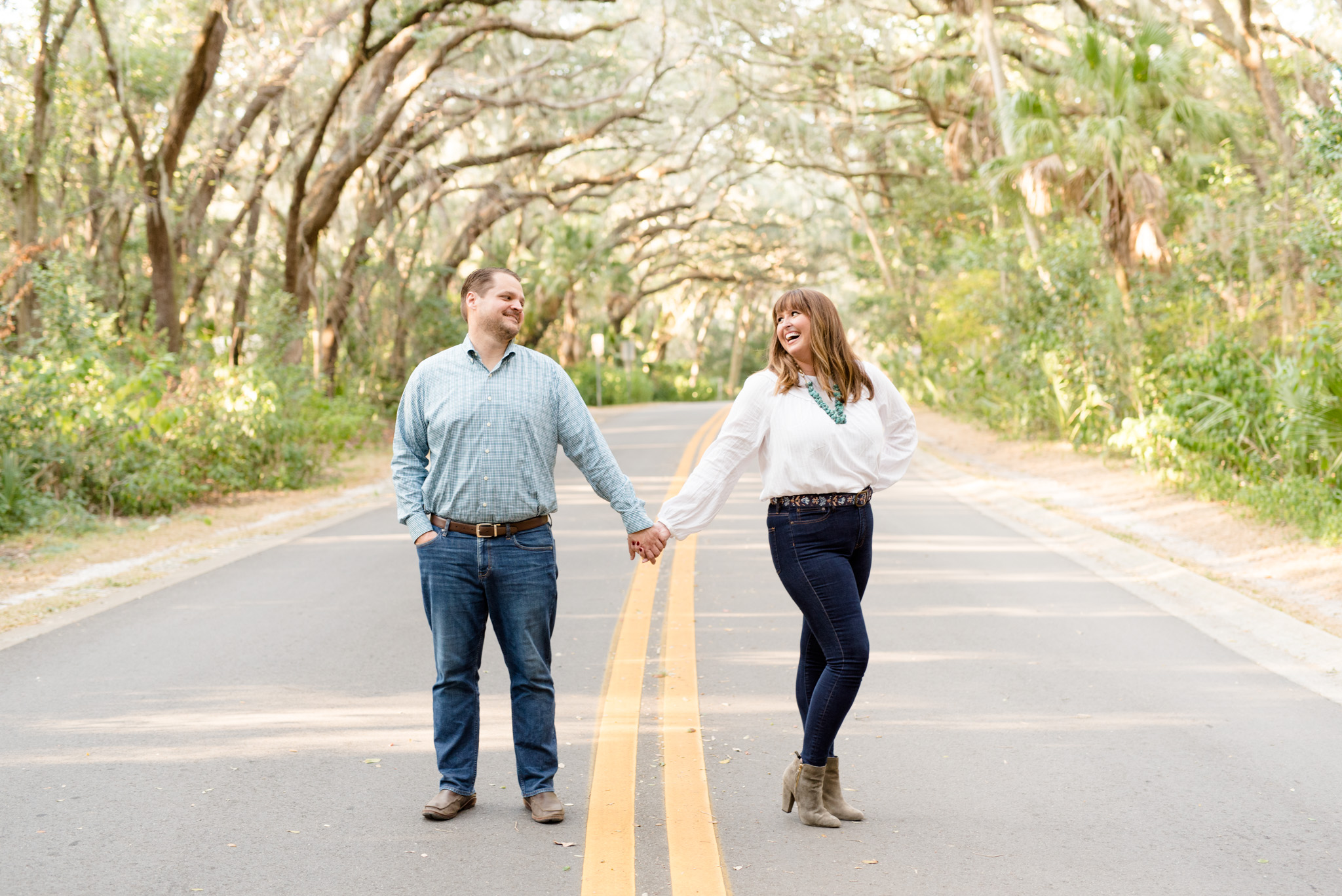 Engaged couple laughs while standing in road.