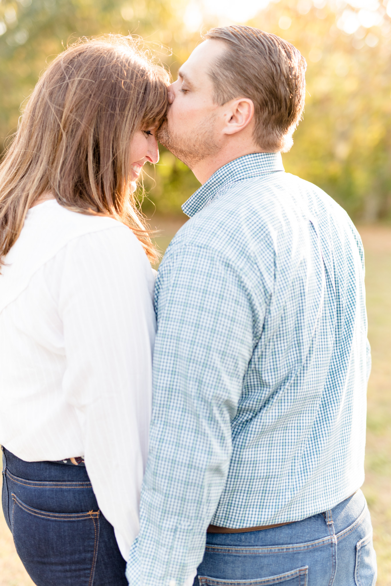 Man kisses bride-to-be on forehead.