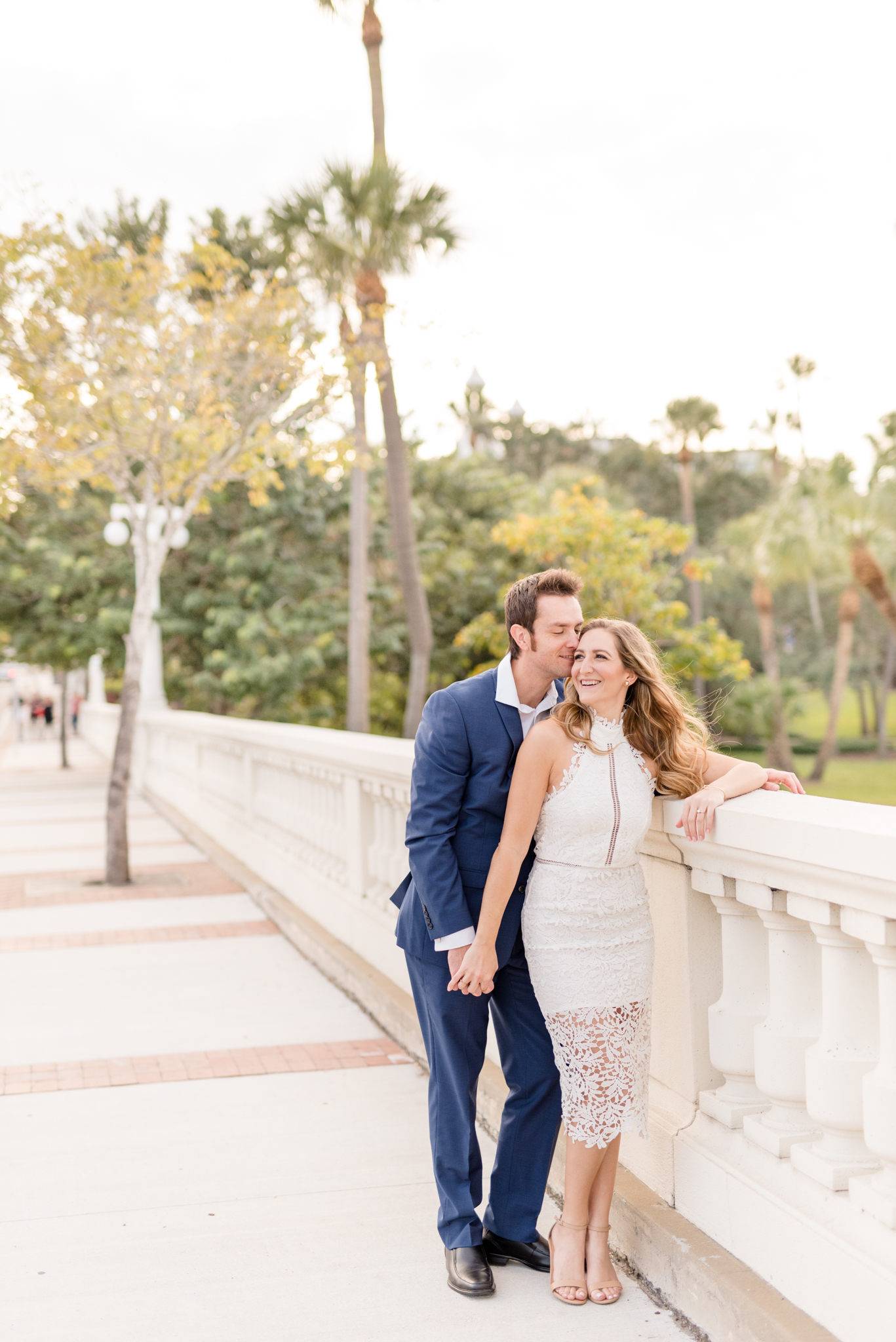 Couple laughs together on stone bridge.