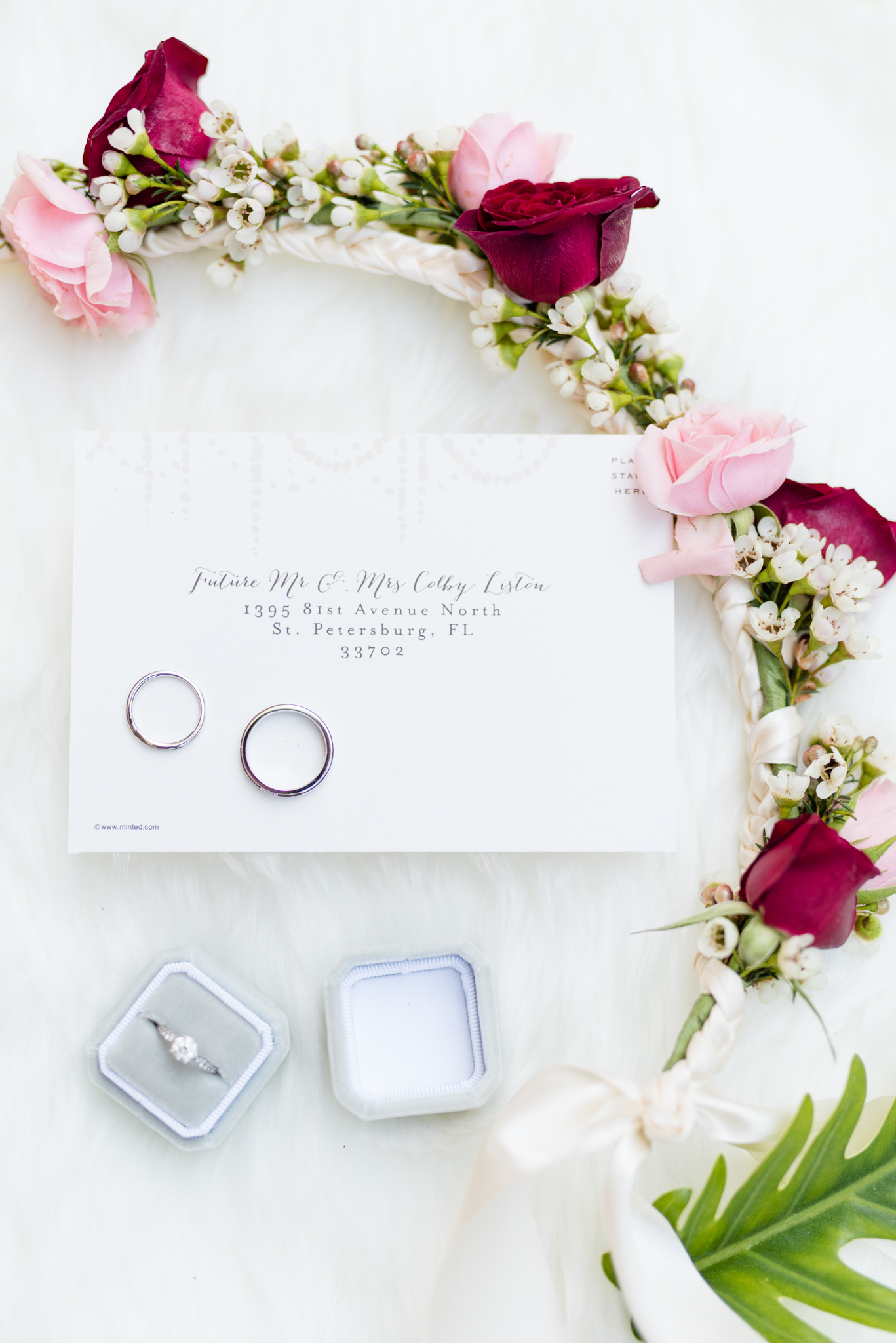 Rings and florals sit on invitations.