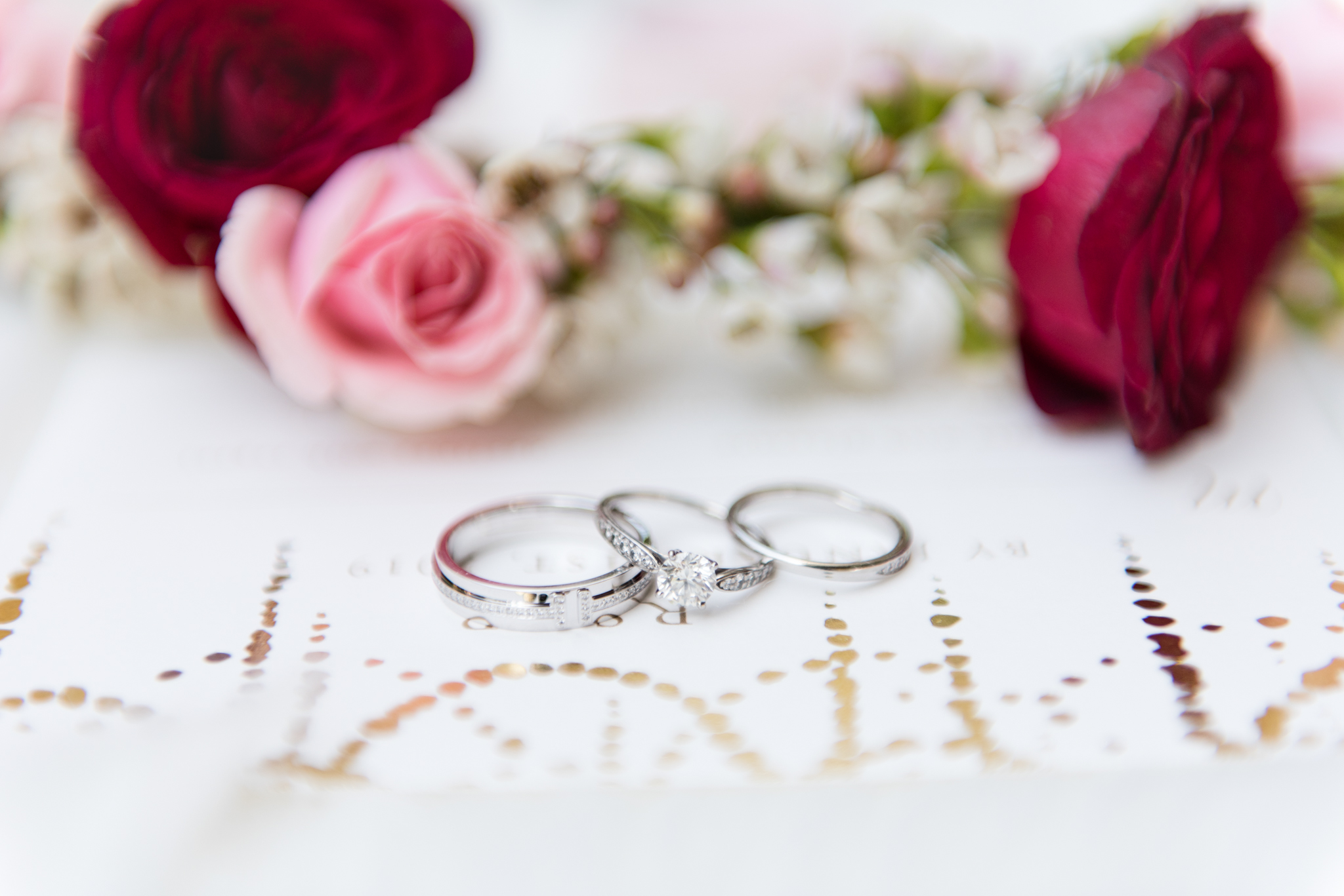 Wedding rings sit on invitations.