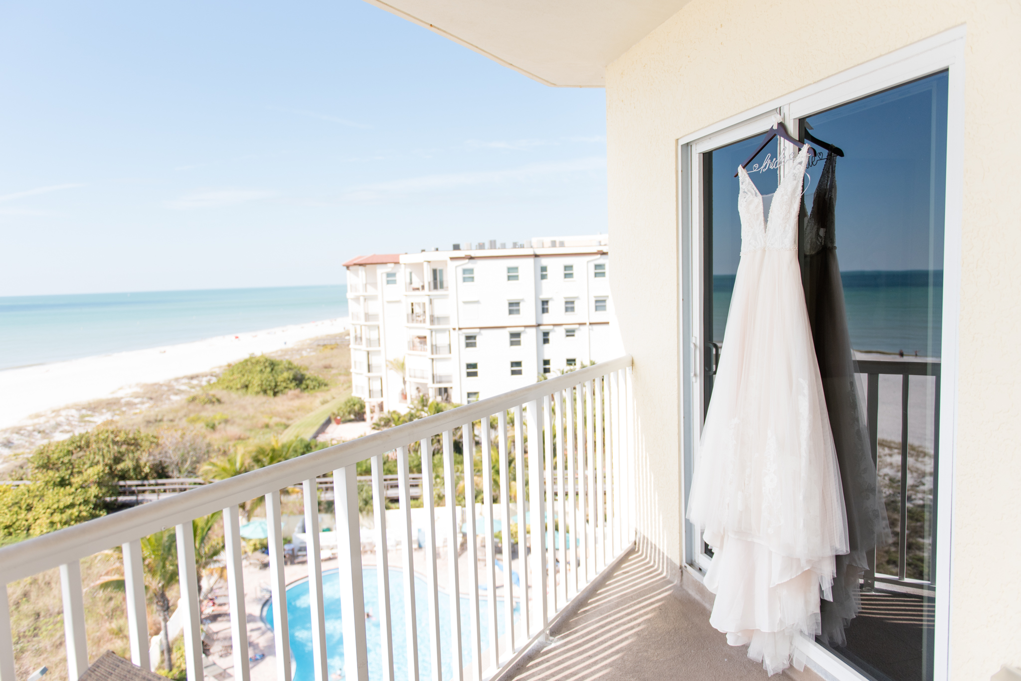 Wedding dress hangs on beach balcony.