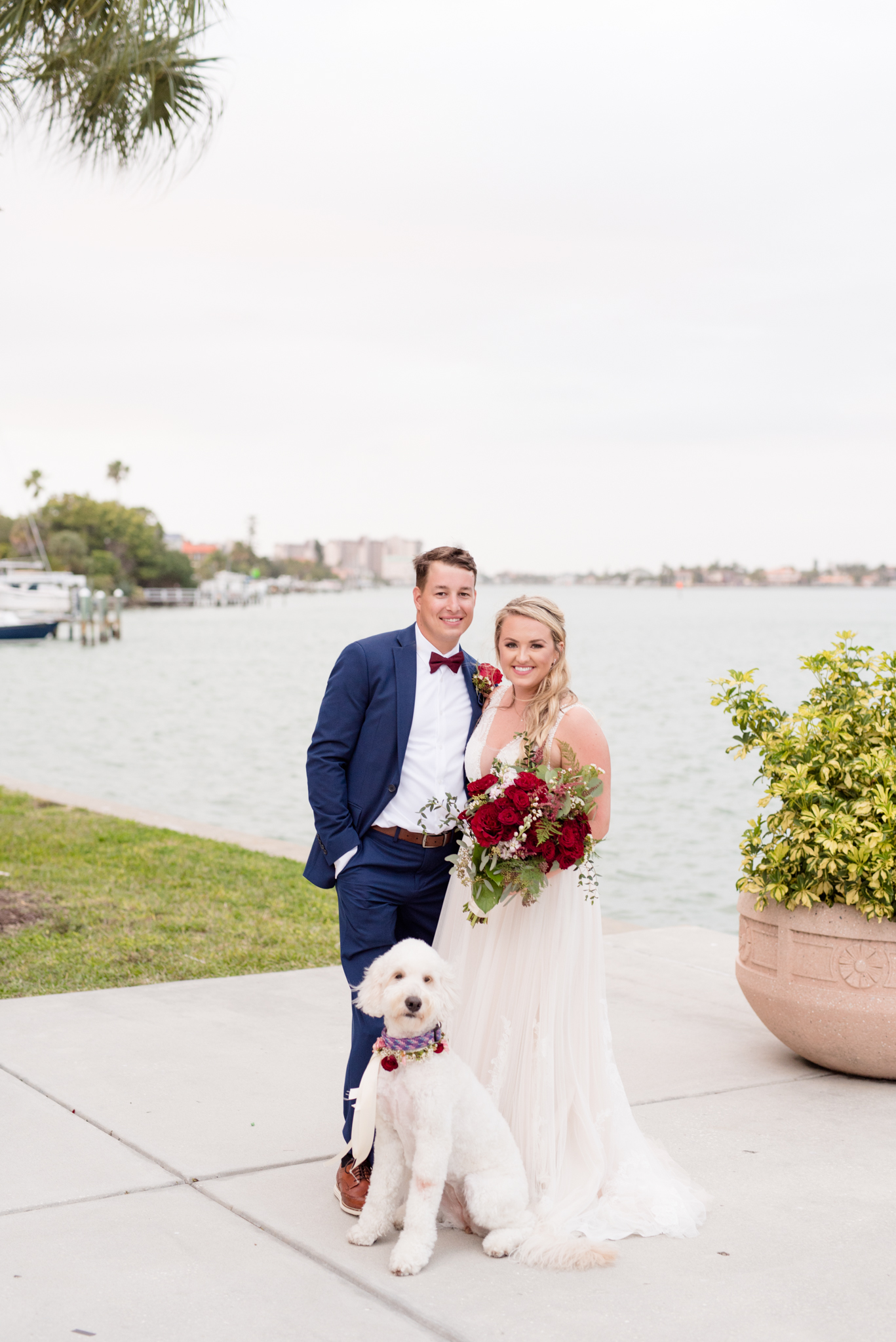 Bride and groom smile at camera with goldendoodle.